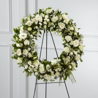 Solitude Wreath - A standing wreath spray to express your peaceful grievances! Send this bouquet of all white roses, lisianthus, monte casino &amp; freesia arranged with elegant foliage &amp; raffia strands.    Approximately   22&quot; Diameter