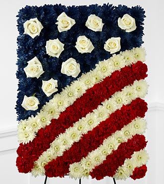 Glory Be Flag Tribute  - The Glory Be Flag Tribute is a symbol of patriotic beauty to commemorate the life of your loved one at their farewell service. Red carnations, white chrysanthemums and blue dyed white chrysanthemums create a stirring arrangement in the likeness of the American flag with white rose accents to symbolize the stars.