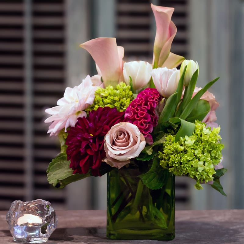 Mixed flower arragement  - Calla lilies, roses,dahlias and coxcomb when seasonally available, tulips and hydrangea in a green-glass cube. Premium blooms.