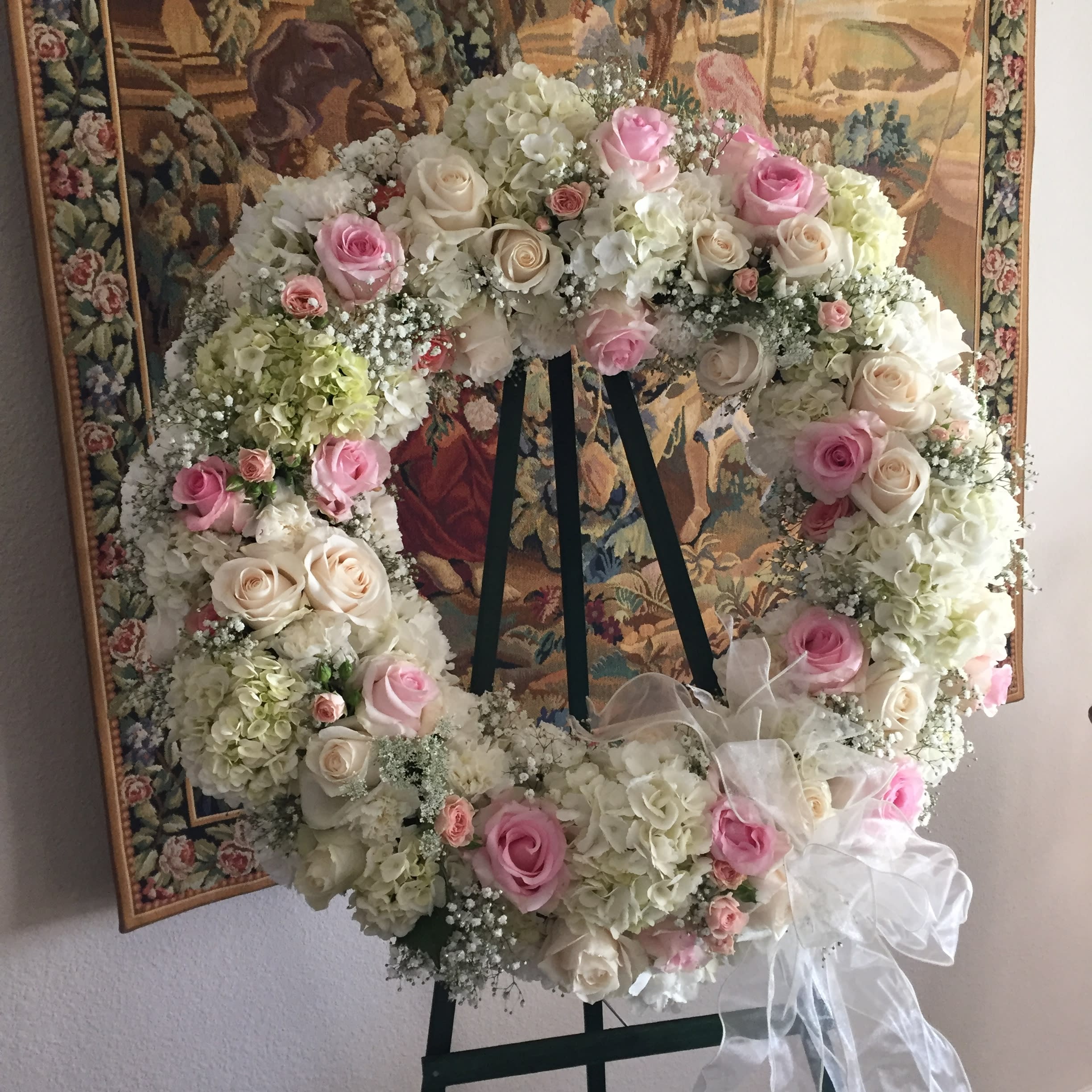 Pastel Serenity Wreath - A softly feminine selection of white and pastel roses and accents make up this sympathy wreath for an overall diameter of about 30&quot;. Delivered on a stand. Overall height is approximately 60&quot;. 
