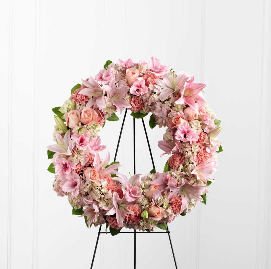 The Loving Remembrance Wreath - The Loving Remembrance Wreath is a blushing display of grace and beauty to honor the life of the deceased at their final tribute. Pink roses, Oriental lilies, gladiolus, hydrangea and carnations are brought together with lush greens to form the shape of a wreath, offering warmth and comfort with its sweetly sophisticated elegance. Displayed on a wire easel.