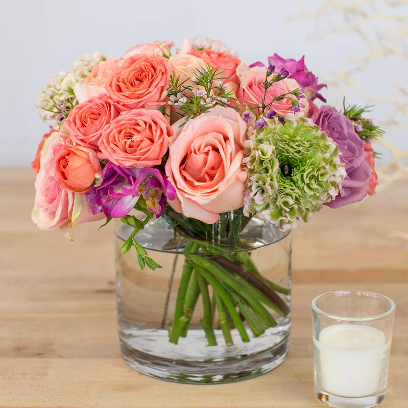Ranunculus and Rose Mixed Arrangement (Clear) Ranunculus and Rose Mixed Arrangement (Clear) - This floral arrangement is full of fresh and vibrant flowers that will brighten up any atmosphere on any occasion. Containers come in clear, white, black, and leaf line.