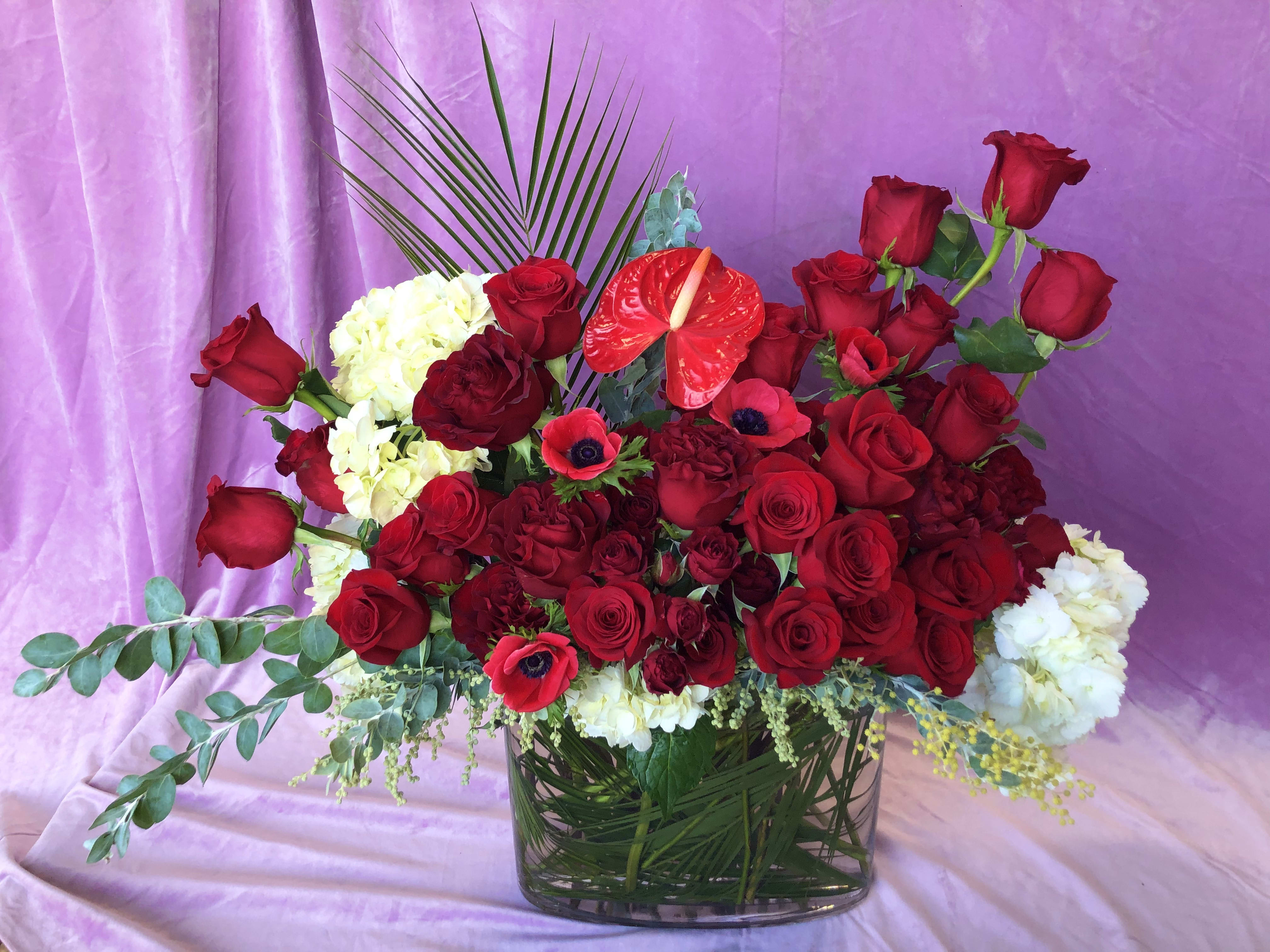 Always Be My Baby - Reds - Variety of red premium blooms in a clear glass 12&quot; oval vase. This full and lush large designer's choice Valentine's Day arrangement is hand crafted in Las Vegas by our all-women design team using the freshest red roses and red garden roses from around the world.  