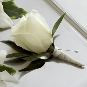 The FTD® White Rose Boutonniere -  The FTD® White Rose Boutonniere creates the classic picture of wedding elegance. A single white rose is chosen for its absolute perfection then accented with lush greens and a white satin ribbon to offer its beauty and sweet fragrance in honor of the wedding celebration. 