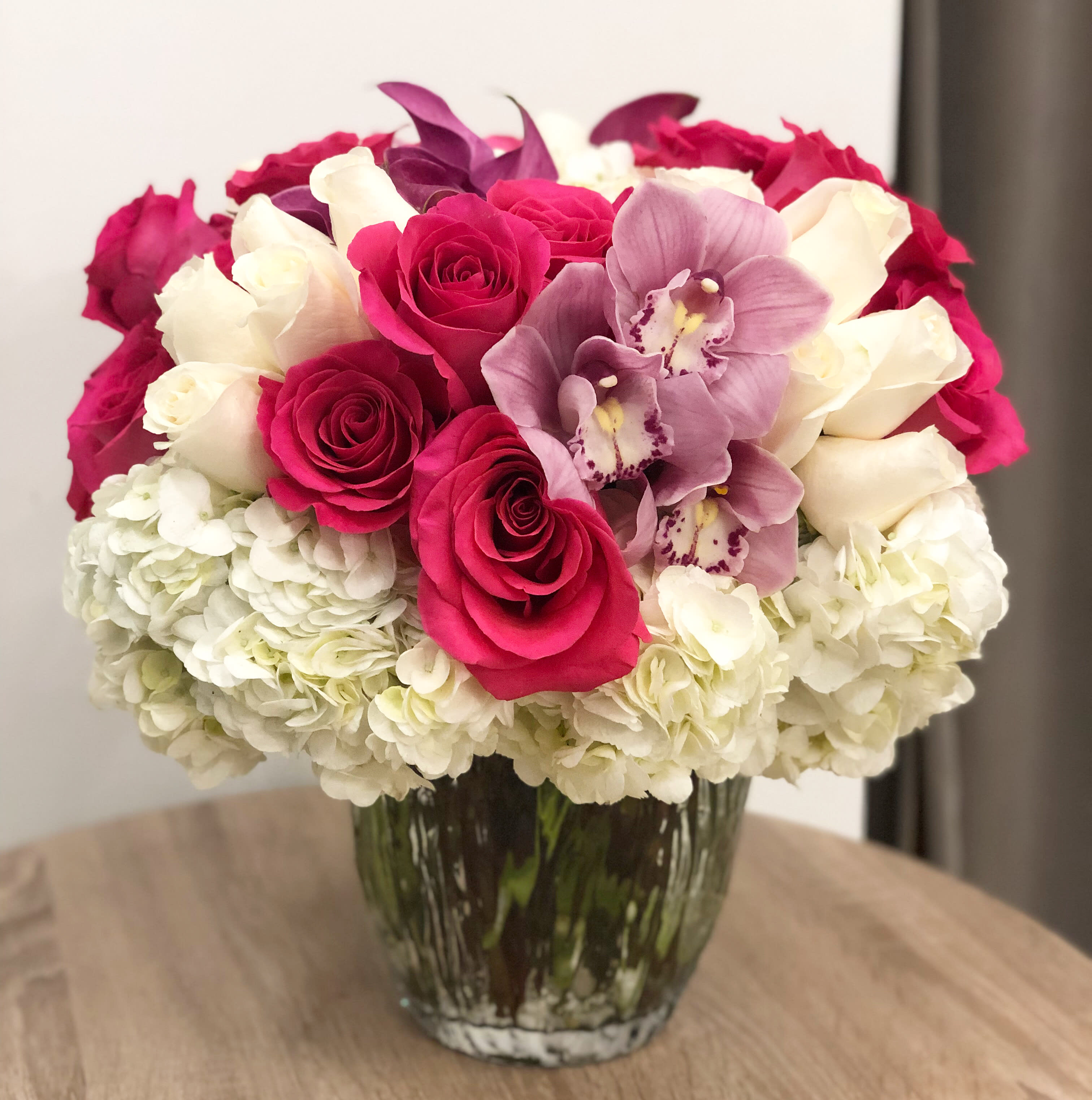 Candy Cane - White hydrangeas, hot pink roses, light pink cymbidium orchid blooms arranged in a 6&quot;Wx 8&quot;W glass vase. Arrangement stands about 16&quot; high. 