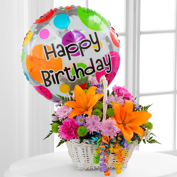 The FTD Happy Blooms Basket - The FTD&reg; Happy Blooms&trade; Basket brings together Asiatic lilies and carnations to create the perfect way to send your happy birthday wishes! Orange Asiatic lilies lavender chrysanthemums lavender carnations purple monte casino asters green button poms and lush greens are beautifully arranged within a rectangular whitewash willow handled basket accented with colorful curling ribbon. Arriving with a bright Mylar balloon exclaiming &quot;Happy Birthday &quot; this flower arrangement will add to the celebration of their special day.