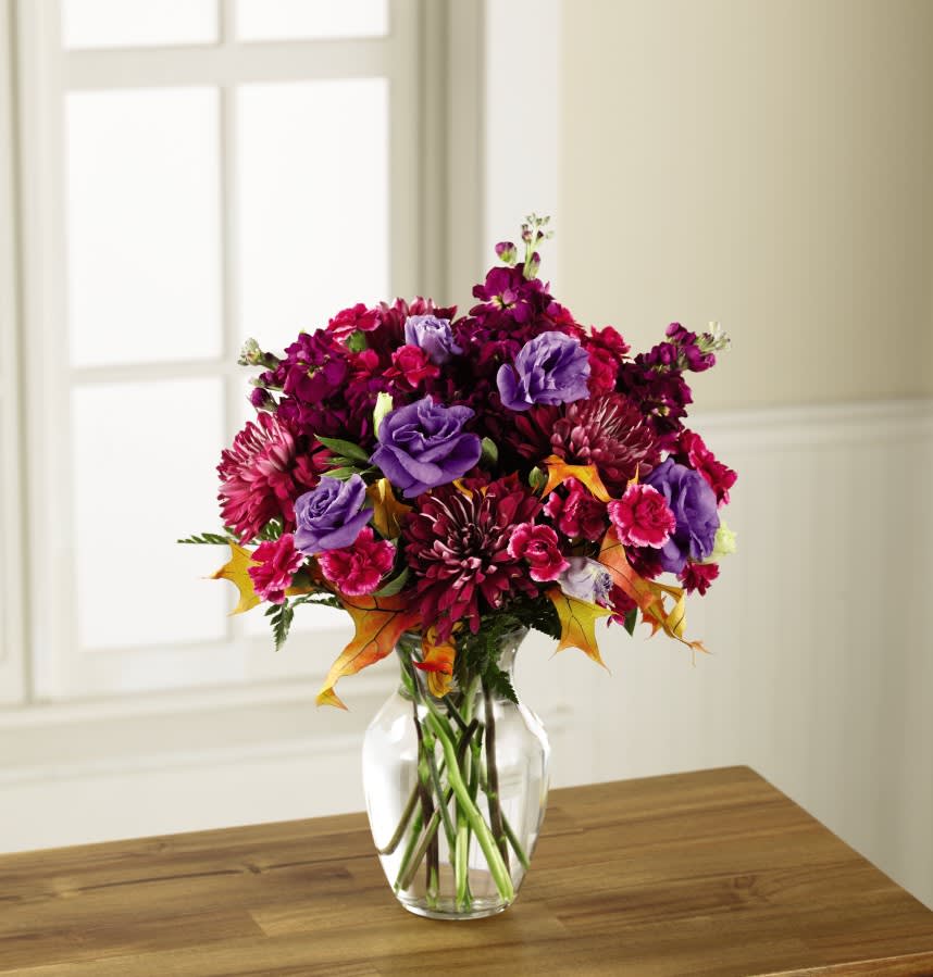 The FTD Autumn Beauty Bouquet - Expressing the very essence of the autumn season with each wonderfully colorful bloom, this fresh flower bouquet has been designed with an artist's eye to help you send a warm and inviting gift. Starting with deep plum chrysanthemums as the base, this arrangement is highlighted by purple gilly flower, purple double lisianthus, hot pink mini carnations, lush green accents, and sunny glycerized oak leaf stems. Presented in a classic clear glass vase this gift of flowers has been designed just for you to help you celebrate Thanksgiving, a fall birthday, or a special anniversary. 