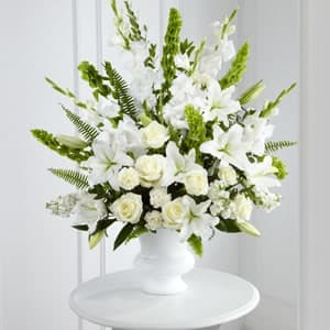 The FTD® Morning Stars Arrangement - The FTD&reg; Morning Stars&trade; Arrangement is a brilliant expression of peace and soft serenity. White roses, carnations, gladiolus, stock, and Oriental lilies are accented with the bright green stems of Bells of Ireland and a gorgeous assortment of lush greens, while seated in a white designer plastic urn to create a beautiful way to honor the life of the deceased.