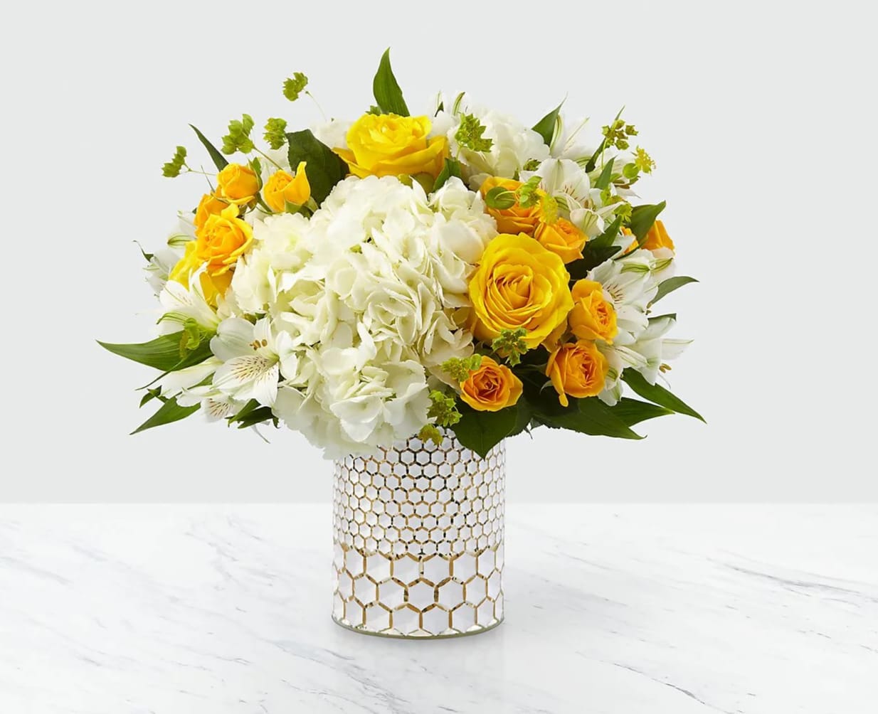 Bees Knees Bouquet - The perfect way to remind the most special people in your life that they're the bee's knees! This bouquet is sweet as can be with a combination of yellow roses and white hydrangea blooms, set nicely in a metallic honeycomb vase. Even better, this gorgeous pick comes right from a local florist!  DETAILS Regular bouquet is approximately 13&quot;H x 12&quot;W Deluxe bouquet is approximately 14&quot;H x 13&quot;W Premium bouquet is approximately 15&quot;H x 14&quot;W  STEMS Hydrangea Rose