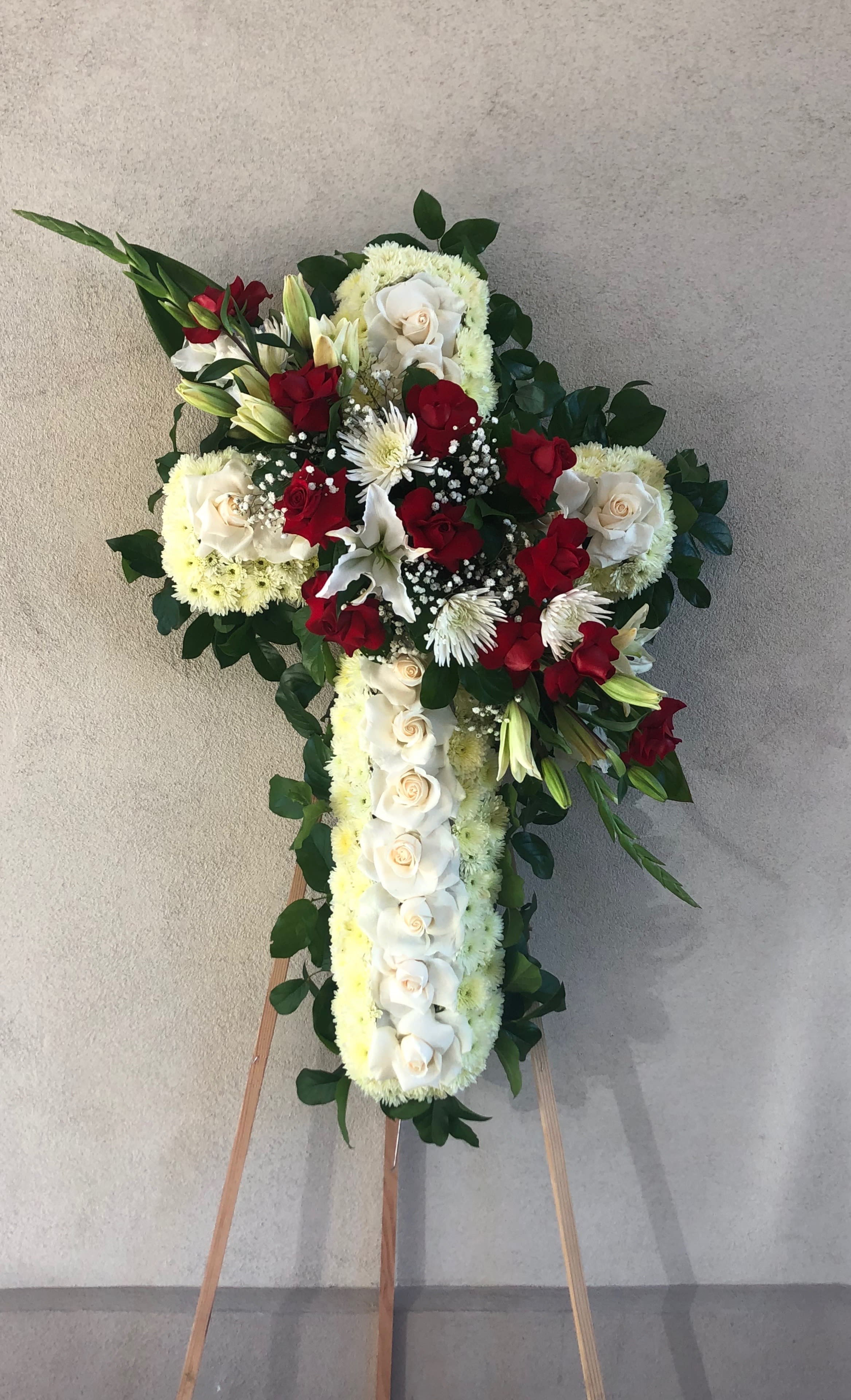Two toned Cross Two toned Cross - Medium Cross with a middle line of white roses , pom pom and lemon leafs. Bouquet in the middle consists of red opened roses, lilies spider flower, gladiolas and babies breath