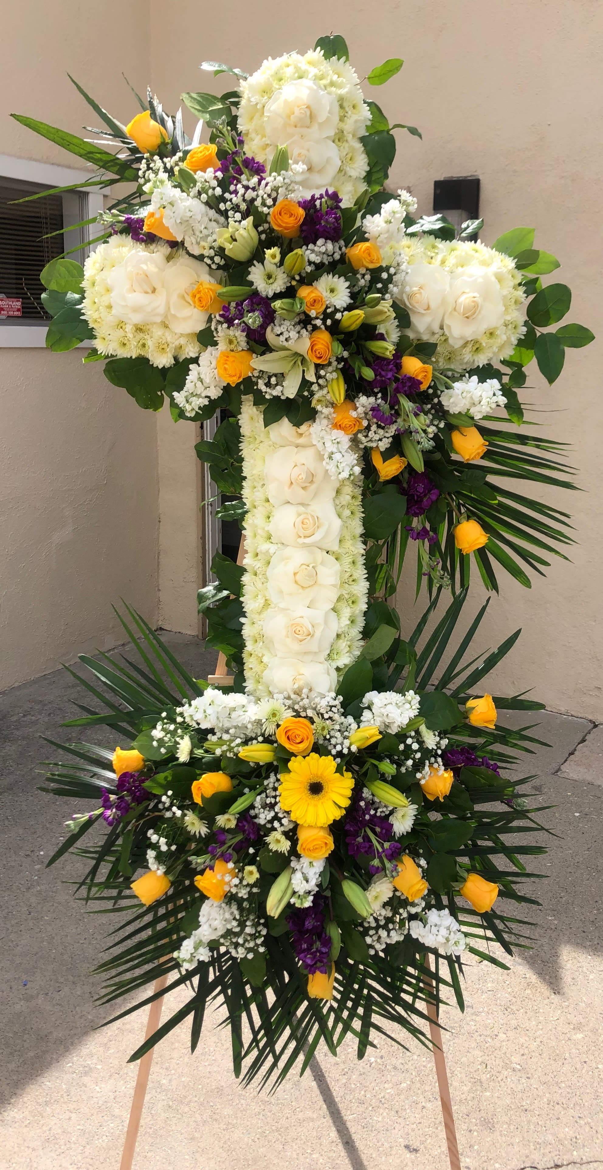 Graceful Cross Graceful Cross - Large cross with roses, stock, pom pom, gladiolas tropical leafs babies breath spider flowers, and lilies We can make this arrangement in any color. Feel free to reach out to us at any time and we will gladly help you.