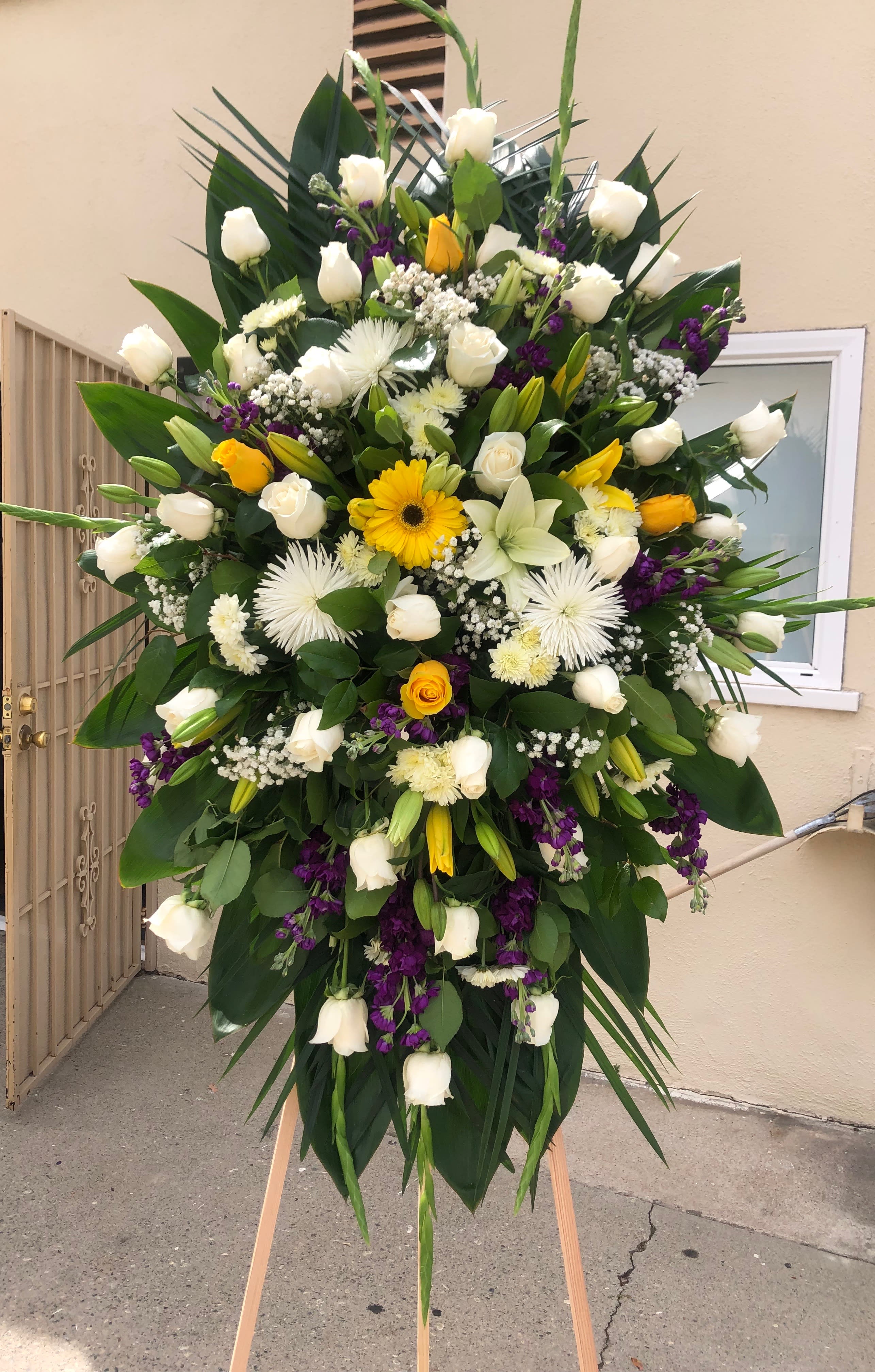 Graceful spray Graceful spray - Large spray with roses, stock, pom pom, gladiolas tropical leafs babies breath spider flowers, and lilies We can make this arrangement in any color. Feel free to reach out to us at any time and we will gladly help you.