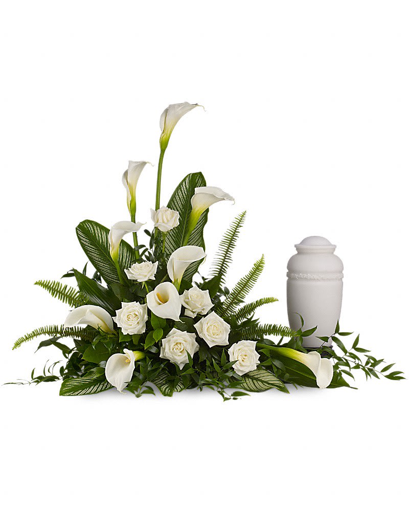 Stately Lilies - A calming portrait in ivory. Majestic calla lilies and stately white roses are framed by the lush leaves of aspidistra and calathea. Soft green sword fern adds to the soothing tones. Large white calla lilies pair with white roses and lush greens that include soft, airy sword fern and glossy aspidistra. Please note: Arrangement does not include urn.