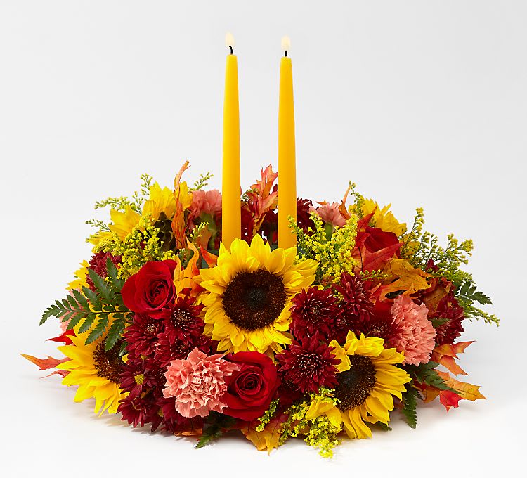Giving Thanks Centerpiece - Complete your tablescape with a centerpiece that is both fresh and charming. Golden yellow candles are surrounded by a mix of sunflowers, roses, and more.  