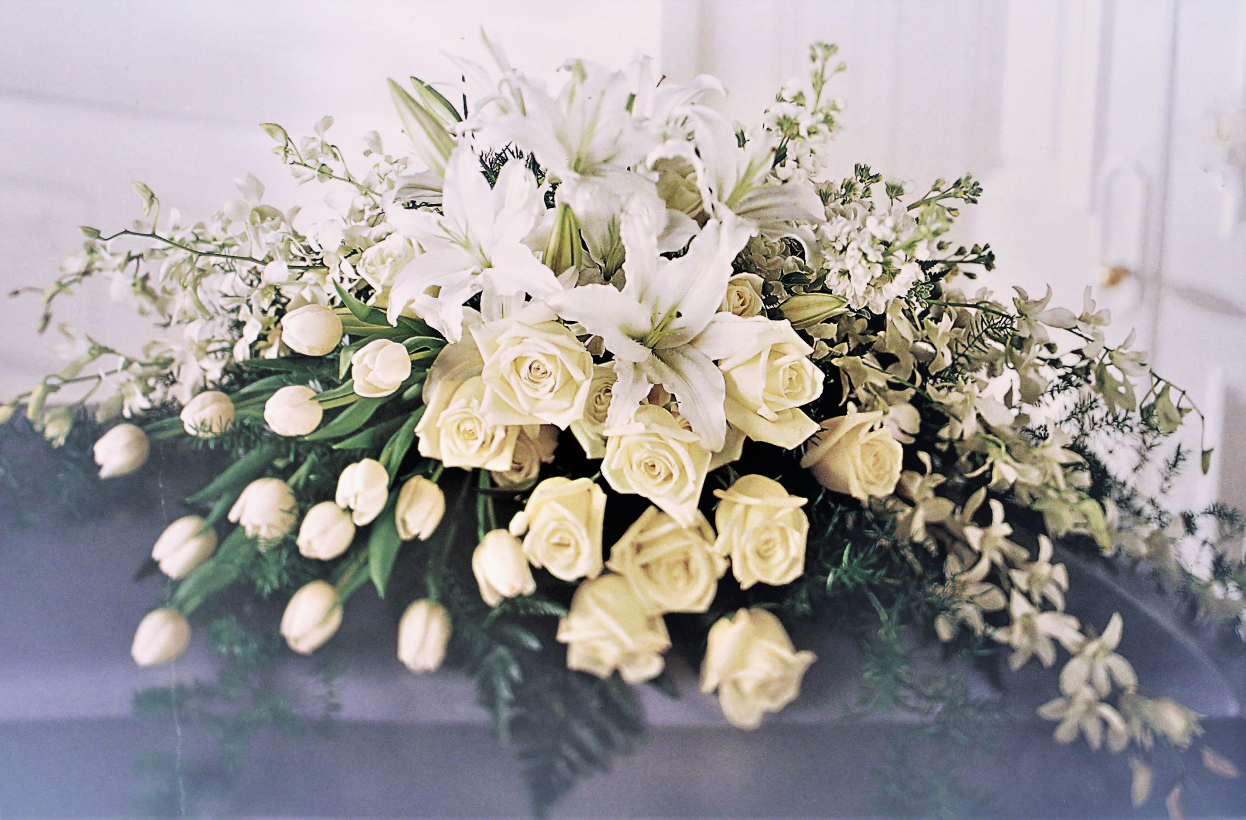 Peaceful Tribute Spray - An elegant mix of all white flowers including orchid's, lily's, tulips, and roses styled in a modern design.
