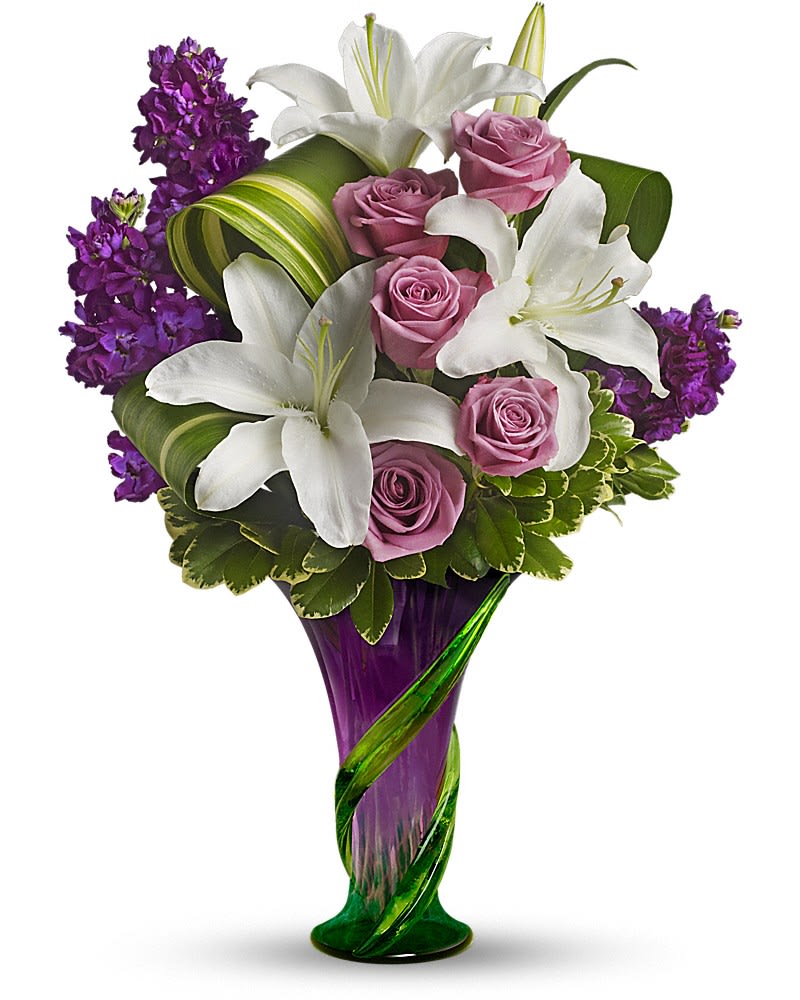Teleflora's Indulge Her Bouquet Teleflora's Indulge Her Bouquet - Go glam for Mom with gorgeous lilies and roses in a chic purple hand-blown art glass vase accented with a curling green vine.She'll be thrilled with this delightfully dramatic gift - and love you for knowing she would be. The stunning bouquet includes white lilies, lavender roses and purple stock accented with assorted greenery.Delivered in a contemporary hand-blown purple art-glass vase with a green climbing vine motif.