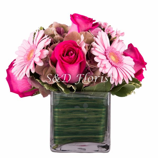 Adelina - In a 4&quot; square glass vase lined with ti leaf containing pink/green hydrangea, hot pink roses, pink gerbera daisy and pink godicia.  Dimensions: 10&quot;T x 9&quot; W