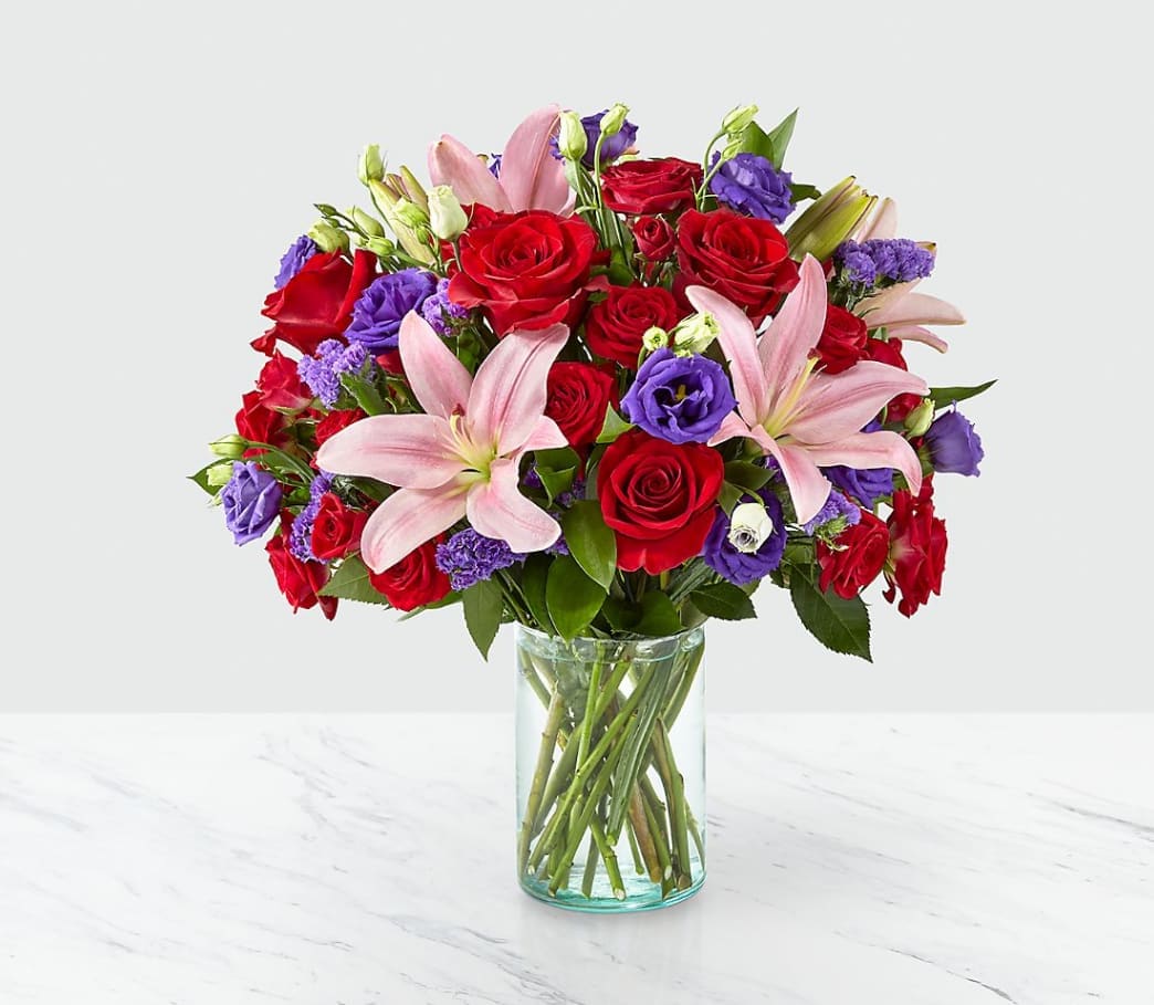 Truly Stunning Bouquet Truly Stunning Bouquet - Share a smile with your loved ones through a bouquet filled with stunning beauty and heartfelt joy. Comprised of vivid red roses, purple double lisianthus, pink lilies and red spray roses within a clear glass vase, vibrant color bursts from every bloom. Make their day brighter with a gift that is Truly Stunning!
