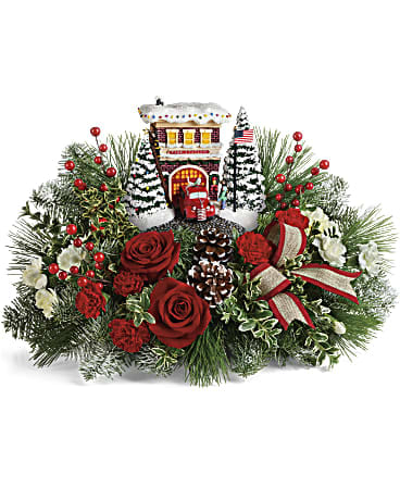 Thomas Kinkade's Festive Fire Station Bouquet - An instant holiday classic! Capture the vintage charm of small-town Christmas with this this festive Thomas Kinkade fire station sculpture. Set atop an arrangement of red roses and fresh winter greens, the hand-painted keepsake lights up for years of fun! This charming gift features red roses, white carnations, red and white miniature carnations, oregonia, noble fir, and white pine. Delivered with a Thomas Kinkade's Festive Fire Station Keepsake.