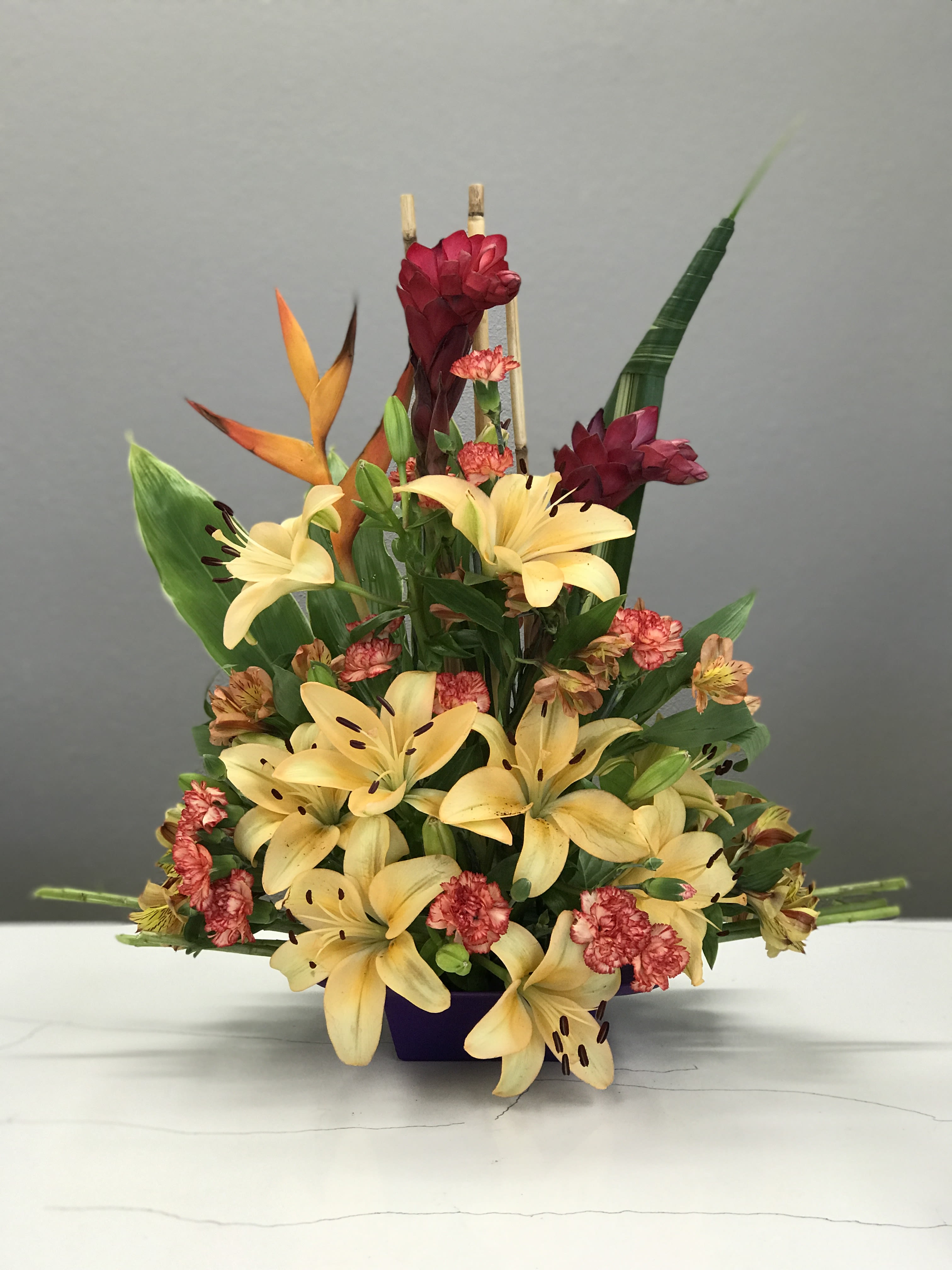 Golden Paradise Golden Paradise - Tropical greens coupled with Birds of Paradise and Red Ginger are serving drama and flare amongst the bursts of tangerine lilies. Perfect for a post Paradise vacay, Just Because, or anyone in need of a serious day brightener.