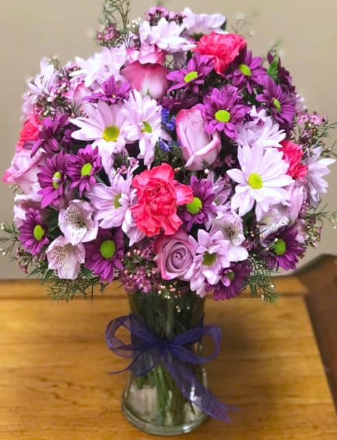 Lavender and Purple Bouquet - Lavender and purple daisies, lavender roses, purple wax flowers, lavender alstromeria, purple statice, pink or purple carnations arranged in a vase. NOTE: To make this arrangement more traditional, on Mother's Day Week, we will add more flowers (white daisies) beside all above. 