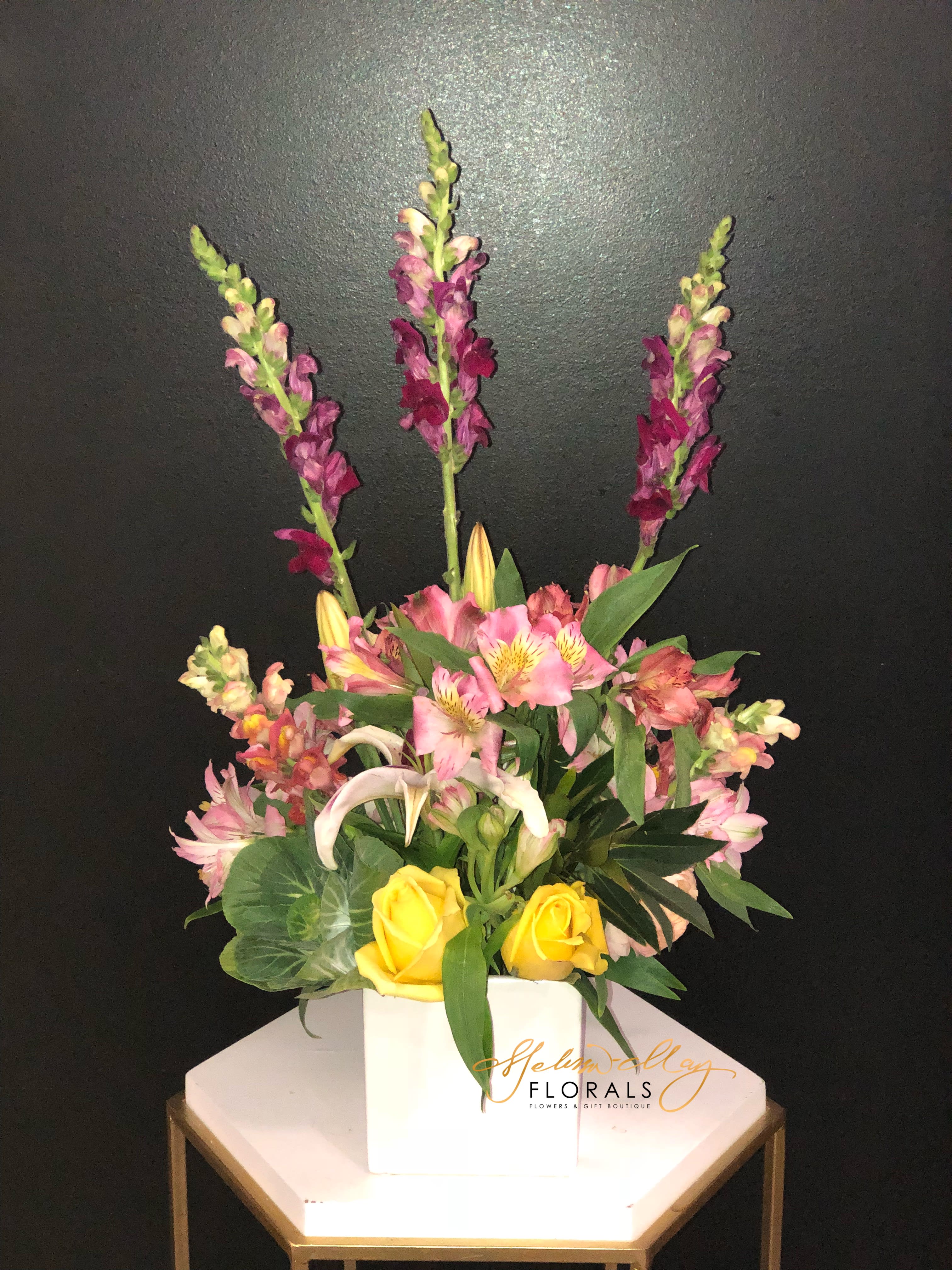 Everything Nice - A free arrangement to enjoy any day in the sun. Its very lively and soothing at the same time. This beauty carries purple snapdragons, yellow roses, lilies and lush greenery. 