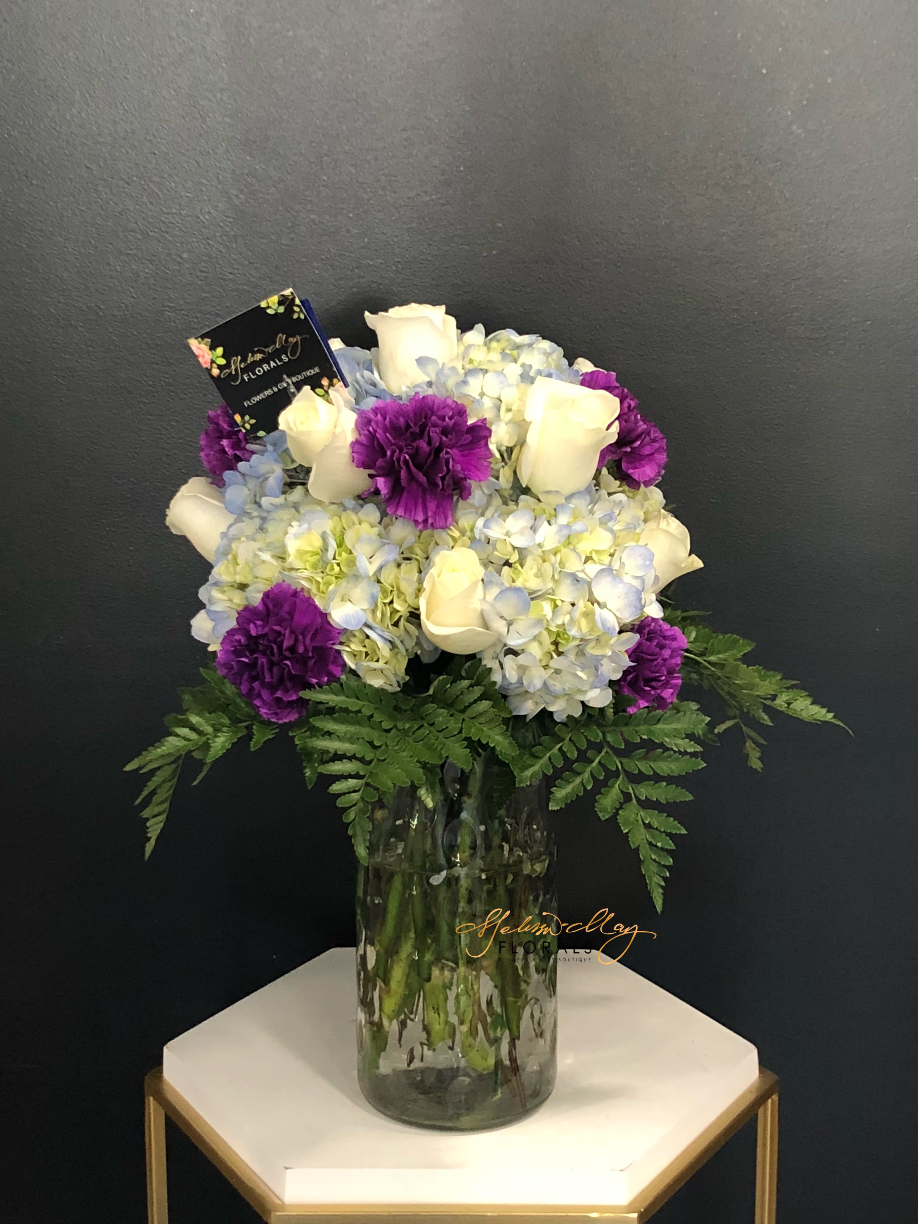 Unconditional Admiration - You will always come and find an arrangement that is just right for you. To show that special someone how much you admire them unconditionally with our purple carnations, hydrangeas, and long lasting white roses.  