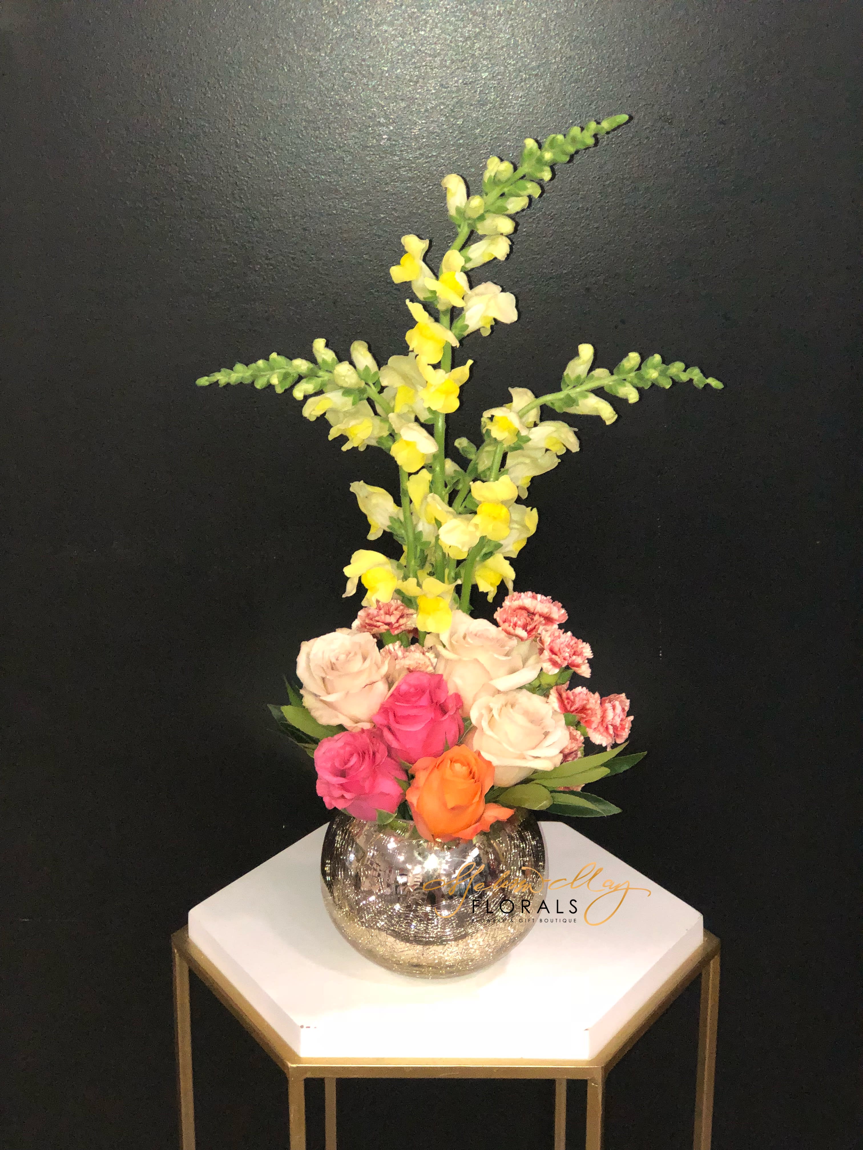 Modern Chic - A customer favorite, this vibrant collection of oranges, yellows, and blush - including roses, snap dragons and much more fragrant hyacinth-is accented with simple greens and designed in our signature crackle glass vase. 