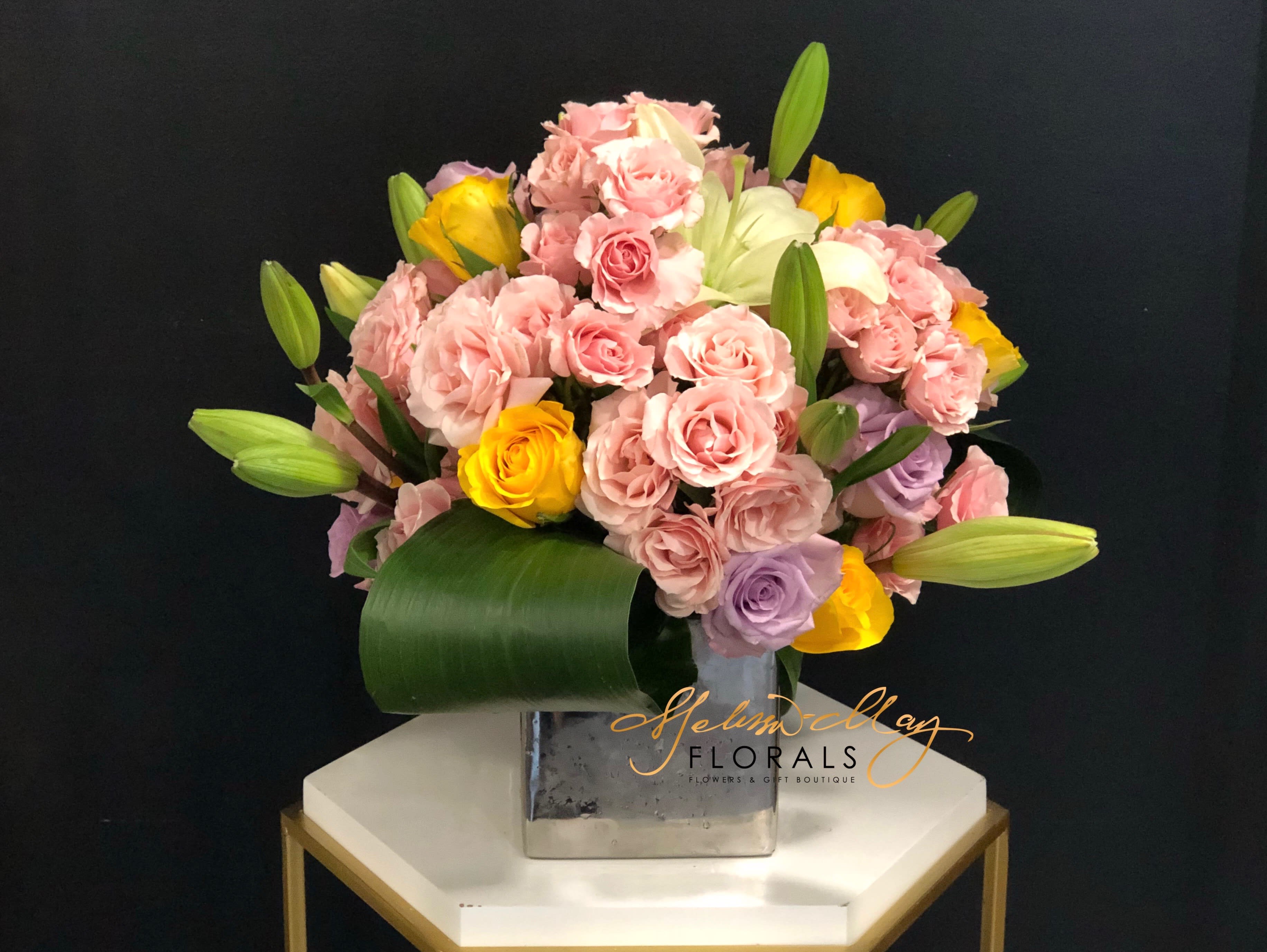Florists Design - An arrangement you will instantly fall in love with, each flower is picked to create the perfect piece just for you. You will find that this the arrangement you always wanted created for you or someone else. The beauty holds the precious pink and lavender spray roses, lilies and lush greenery. 