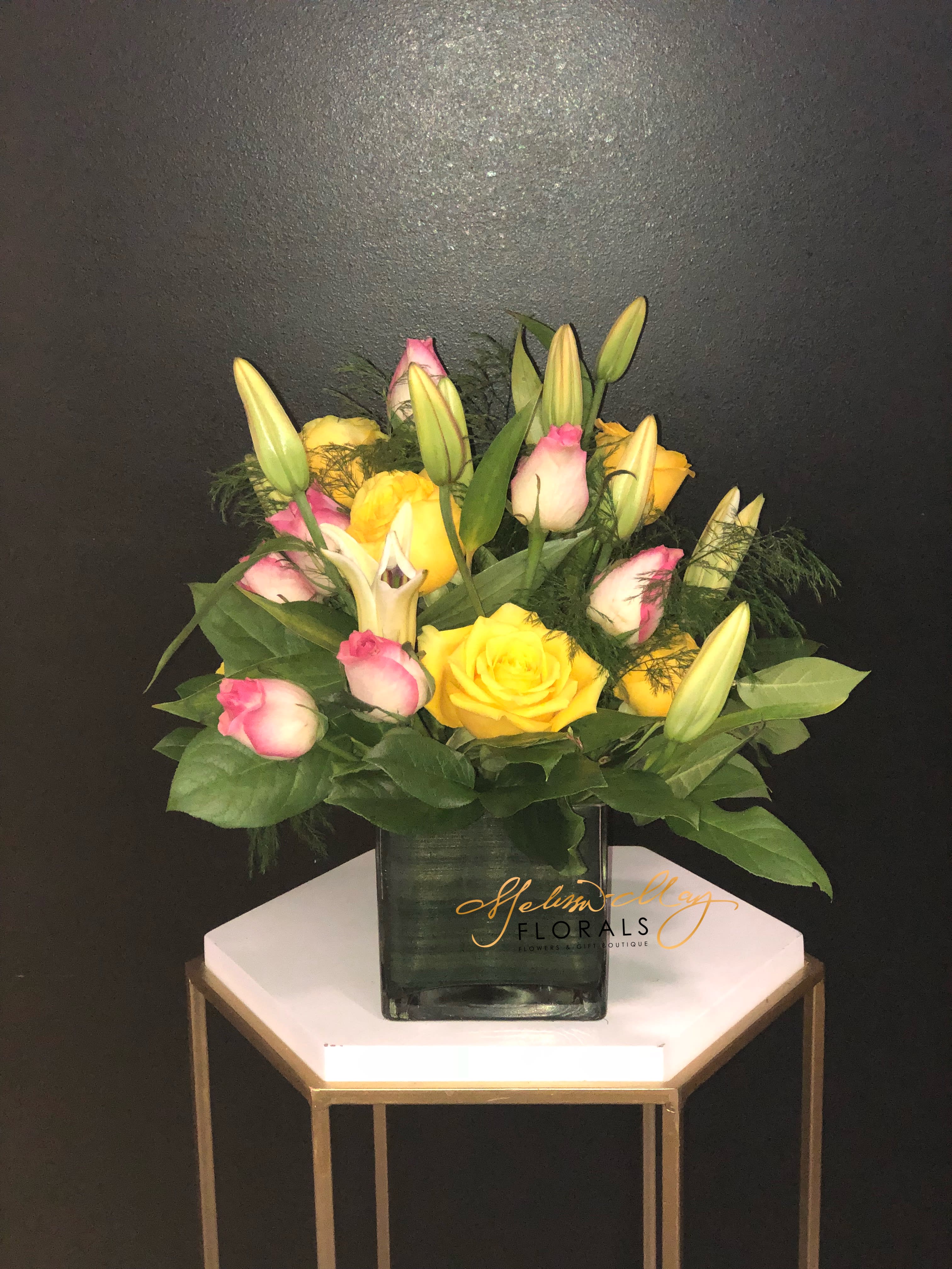 Summer Magic - The feel of summer is always what you want to feel each time you look at this arrangement. Each time you look at this piece you will always be reminded of summer days filled with magic. Come in and grab this beauty filled with sweet pink roses, yellow roses, and lovely lilies. 