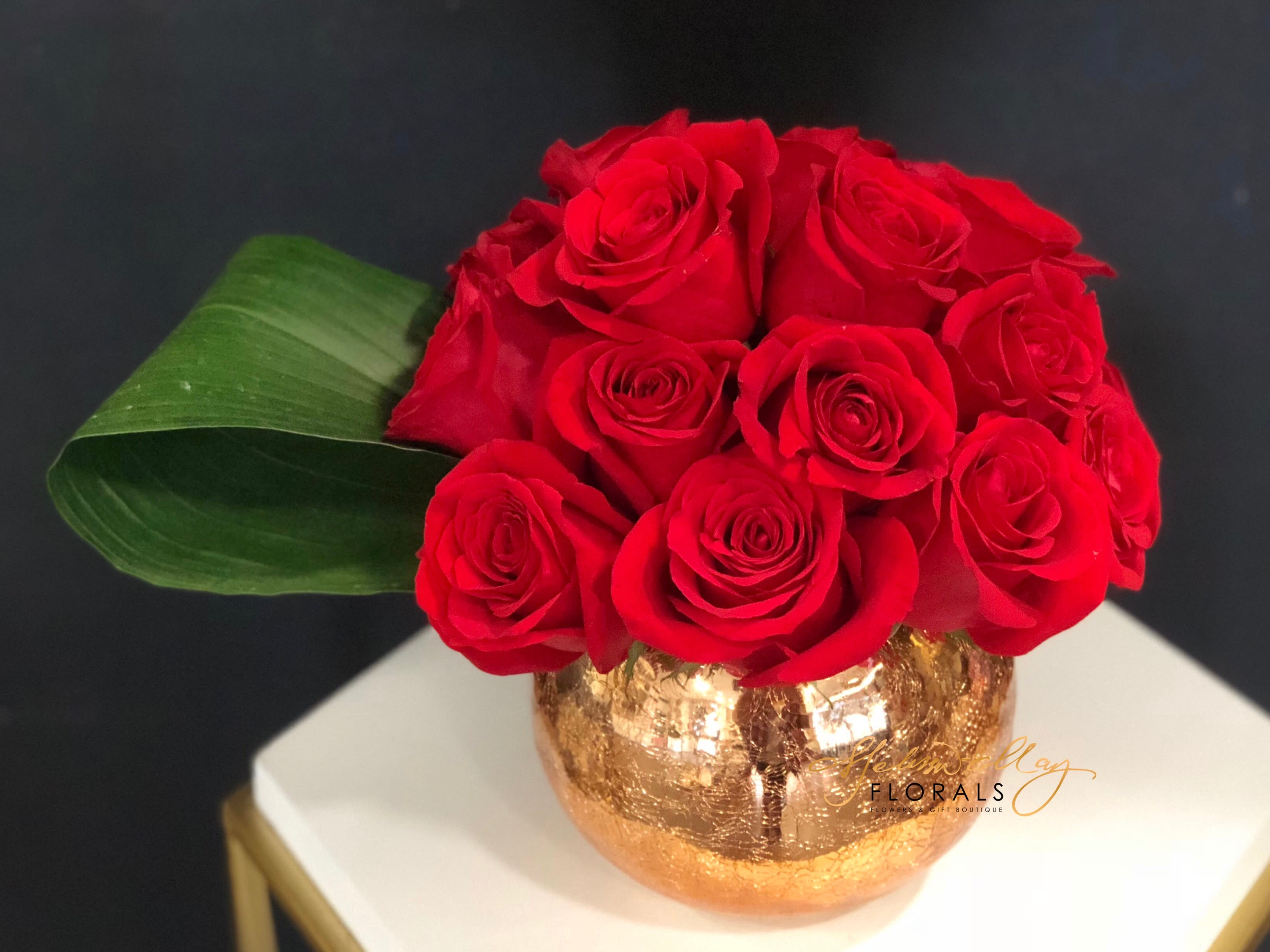 Love is in the Air - Our signature &quot;Love Is In The Air&quot; is a low and lush arrangement of 20 red roses in our mercury rose gold round vase. This arrangement comes with handmade chocolate bark with any purchase. Come inside today to pick up this beauty. 