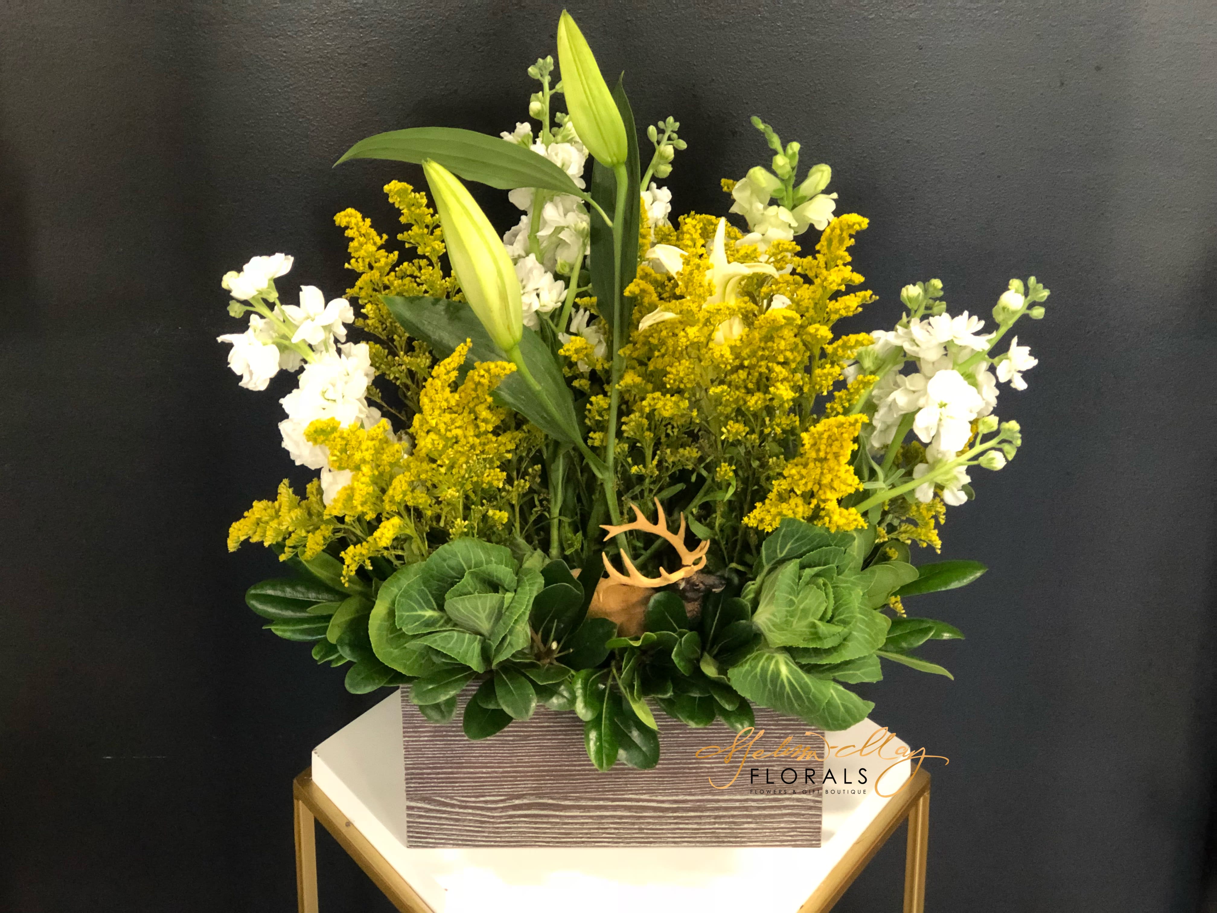 Deer Garden - You can have a deer in your own home and fall in love with every moment of it. An arrangement such as this give you the feel as if you are front and center of a deer in the forest. With white stock and a bountiful of lush greenery.  (Vase in image is no longer available. A substitute will be used.)