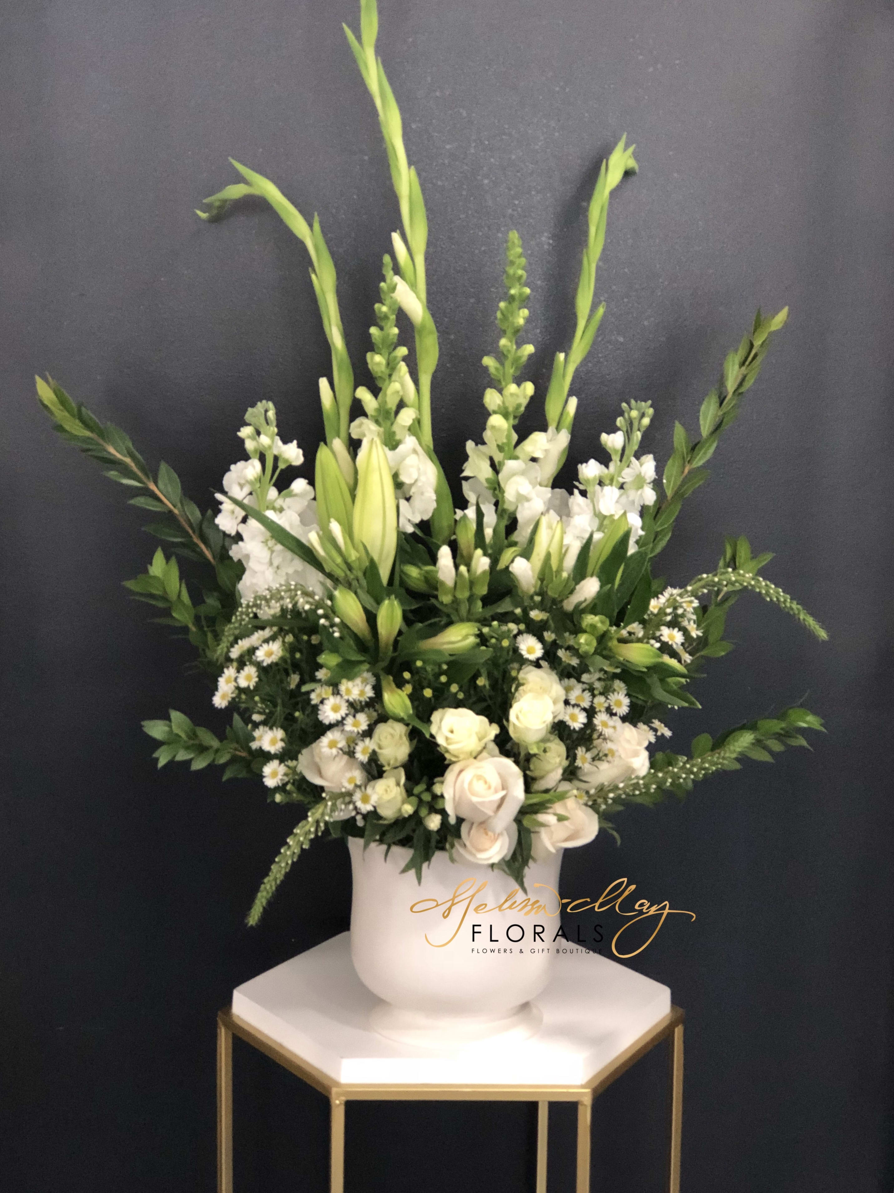 Flowers of Life - A lost of a love one can be hard on you: however do not forget about the times that was most memorable. These flowers will tell you multiple stories that you will never forget during your grievance process. With white roses, white stock, white carnations, white daisies, and so much more.   (Vase in image is no longer available. A substitute will be used.)