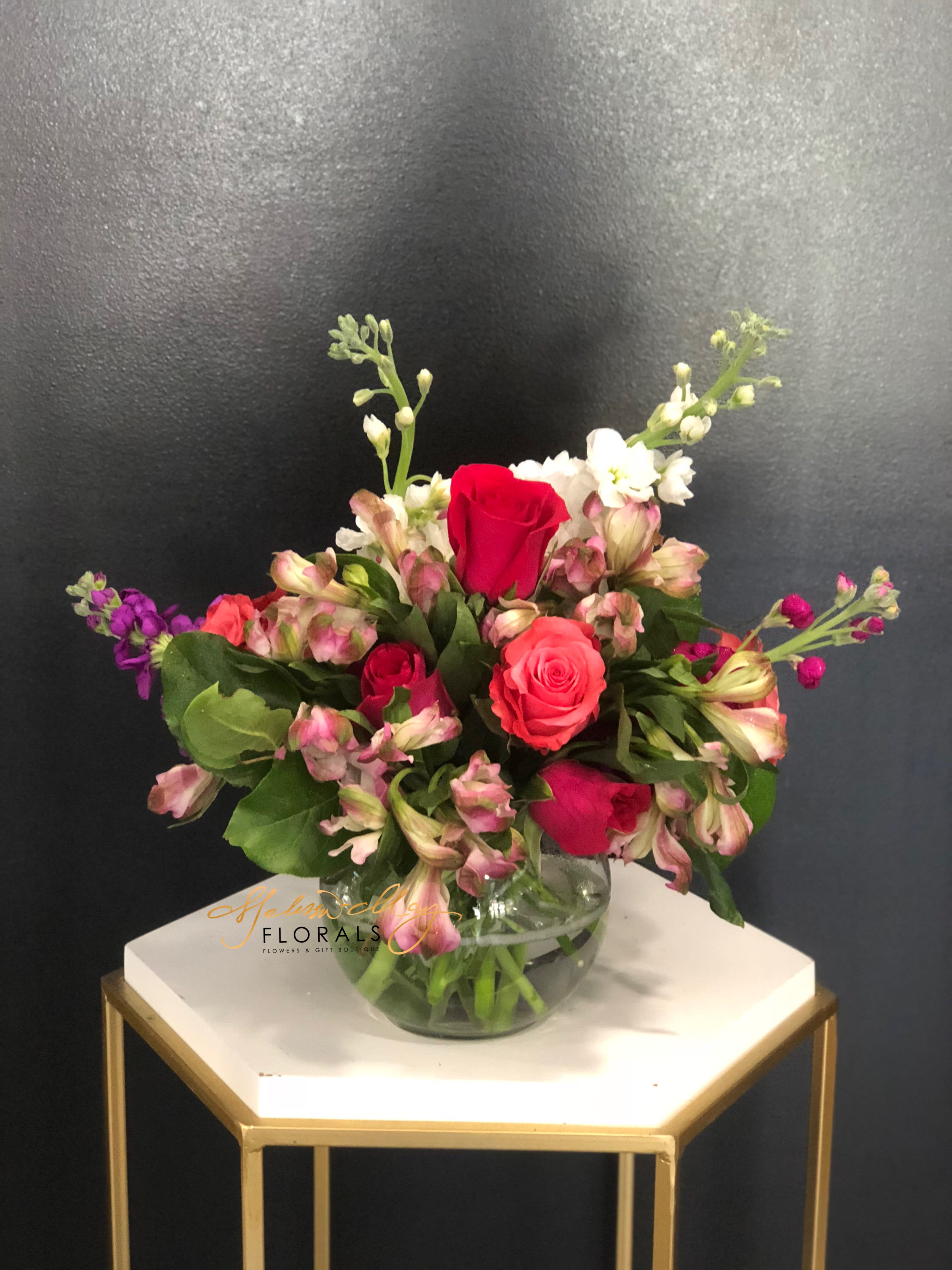 Pretty Girl - A pretty small arrangement for any girl to enjoy. A small piece that will be perfect for a play date or even perhaps the center of a dinner table. It will fit the occasion of anything you want it to. With pretty pink and purple stock, hot pink roses, and pink alstroemerias.  Disclaimer: (Candle in image is not included with order. Must be purchase separately.) 