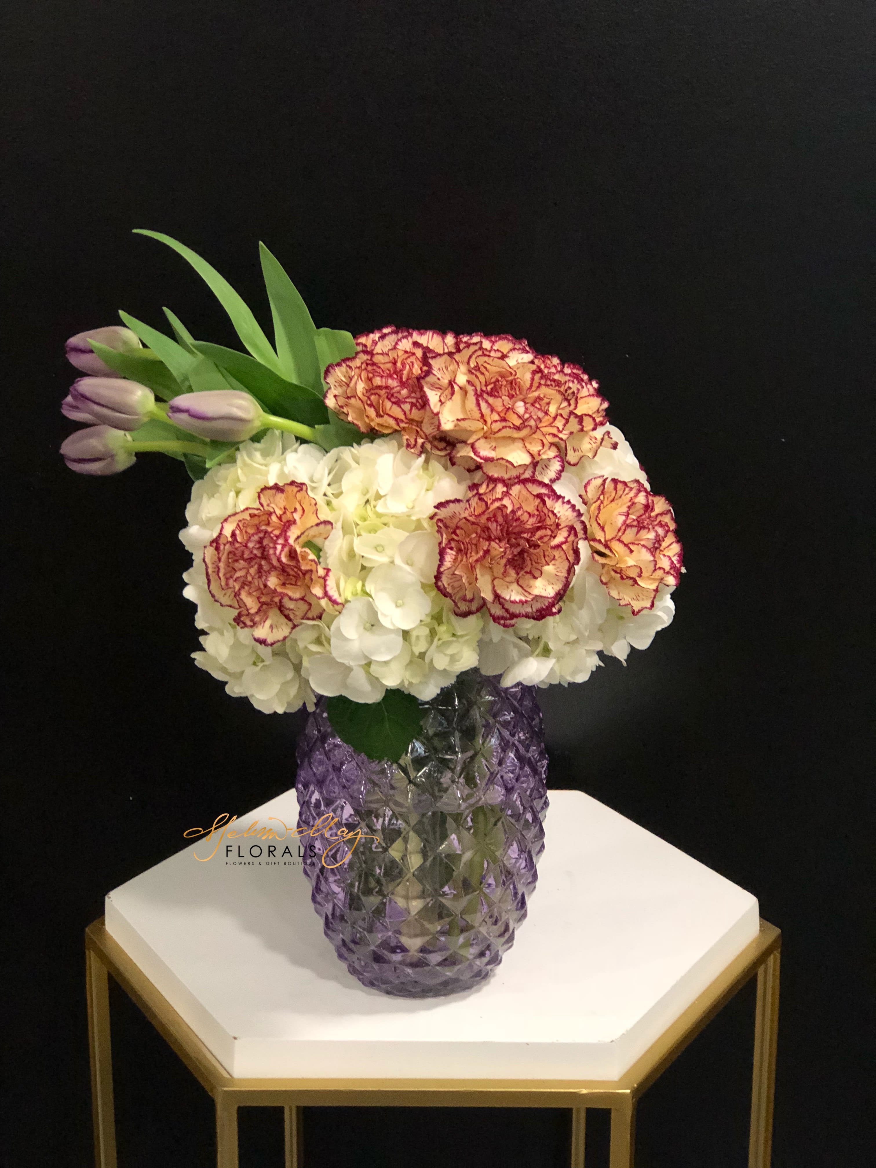 Caring Carnations - Beauty is in the eye of the beholder and everyone will know that this arrangement is the most beautiful creation ever created. What a beautiful piece to have together. We couldn't put all the carnations in the world together so we picked these beautiful carnations and the fantastic purple tulips.  Vase Limited Edition