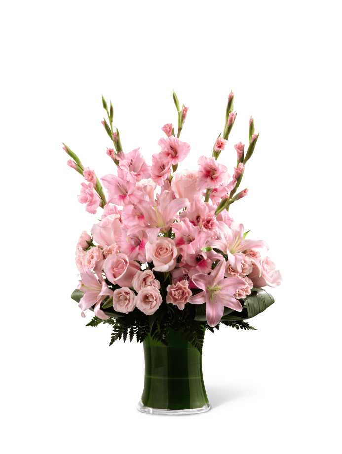 The Lovely Tribute Bouquet - The Lovely Tribute Bouquet is a warm and blushing display of peace and beauty, set to honor the deceased and bring comfort to family and friends. Pink gladiolus, pale pink roses, bi-color pink roses, pink Asiatic lilies and an assortment of lush greens create a sophisticated arrangement seated in a clear glass gathering vase, symbolizing your heartfelt love and sympathy.