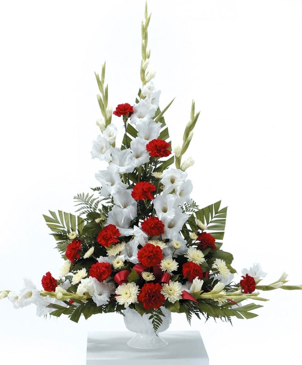 Gladiolus Grandeur - White Gladiolus Soar from a garden of red Carnations, white Cushion Pompons and select garden foliage in this memorable tribute.