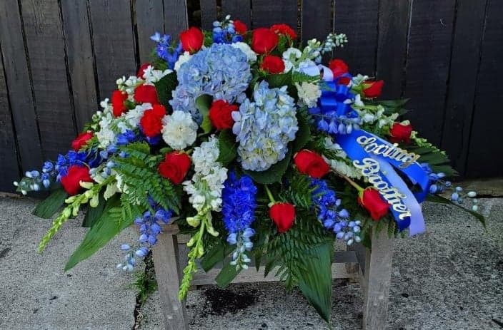 Distinguished Service Casket Spray  - A beautifully patriotic way to pay tribute to a loved one. This half-couch spray sends an eloquent message of strength, respect and freedom. 