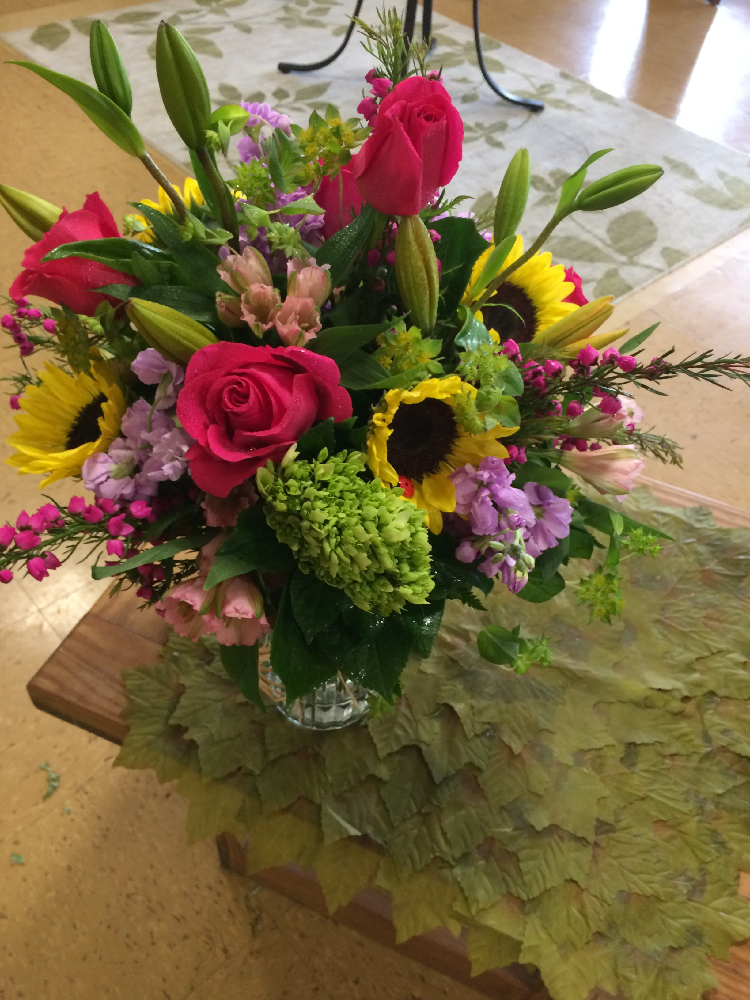 Fresh And Lovely - A bright colorful bouquet perfect for any occasion. Custommade with hot pink roses, sunflowers, and hydrangea, in a glass vase