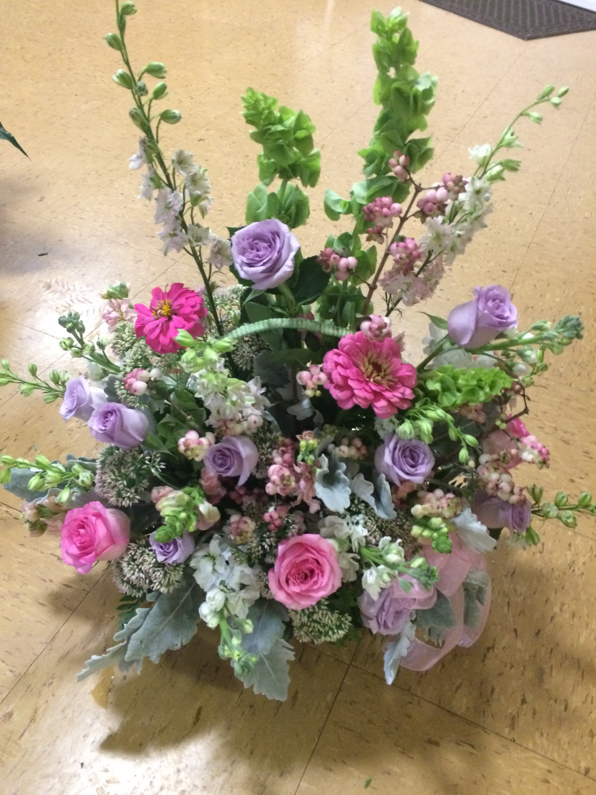 Spring Fling - A soft pastel palette with roses, delphinium, bells of Ireland. A basket arrangemet, that can be used as an alter arrangement for a wedding, or sent as a sympathy tribute.