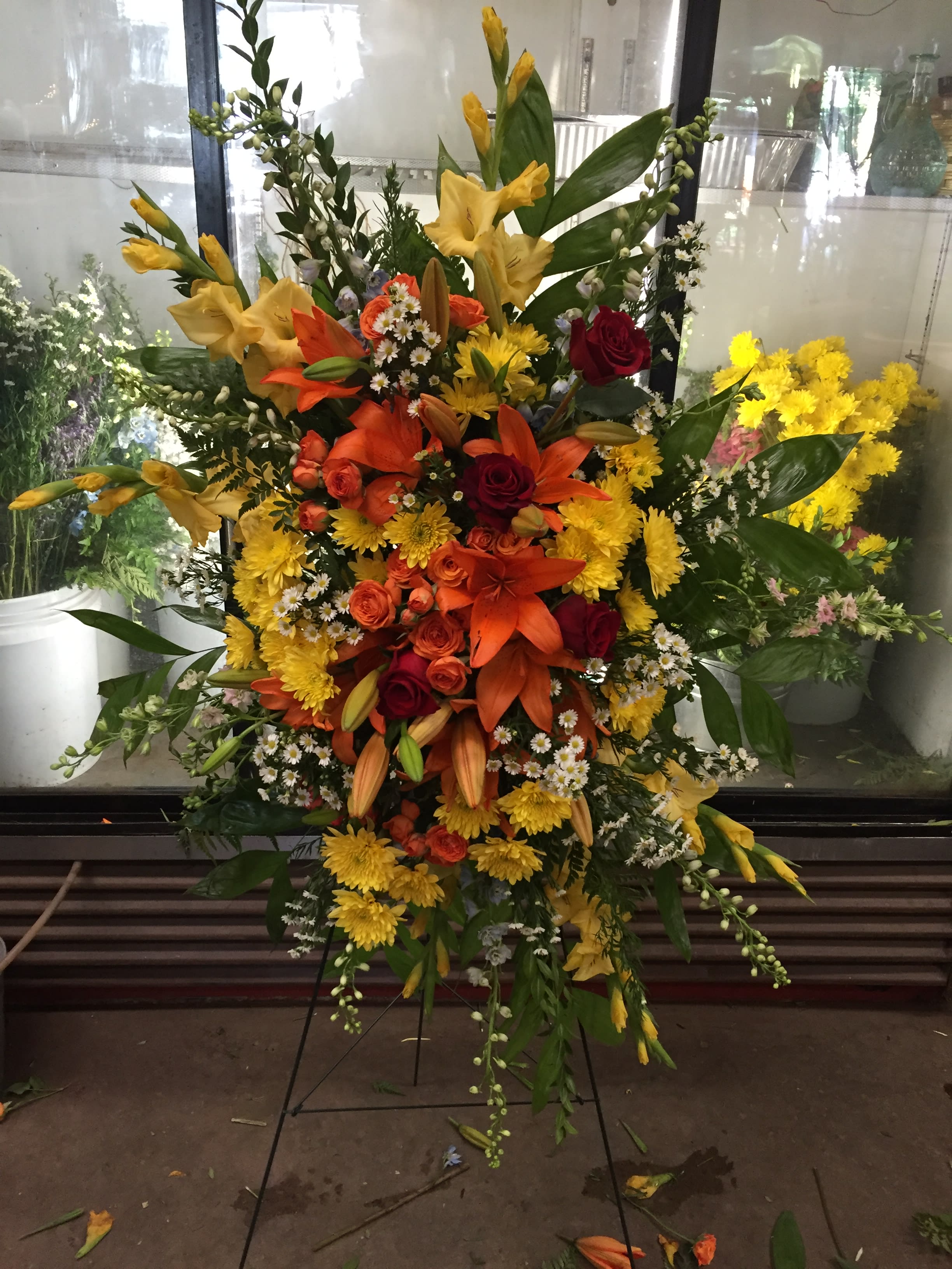 Orange Lilly Spray Orange Lilly Spray - This is a standing spray arrangement it hangs for an easel. This arrangement is full of different reds, oranges, and yellow flowers. You can change the color scheme to what ever you'd like.