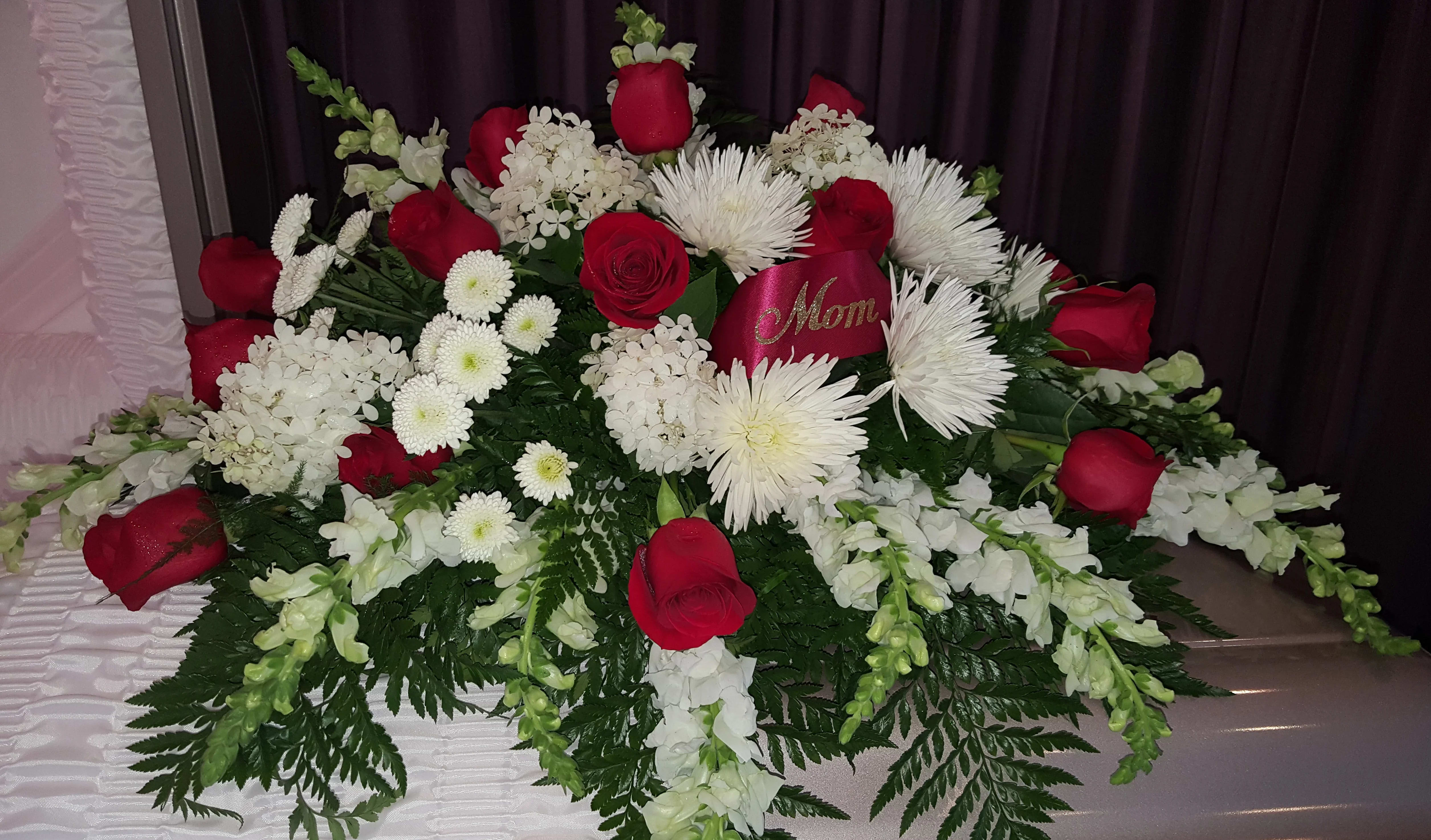 Red and White Delight - This beautiful red and white casket piece is a very elegant and traditional way to represent your loved one. Full of white hydrangeas, snap dragons, spider mum, buttons and red roses. Please order at least 48 hours prior to memorial service. 
