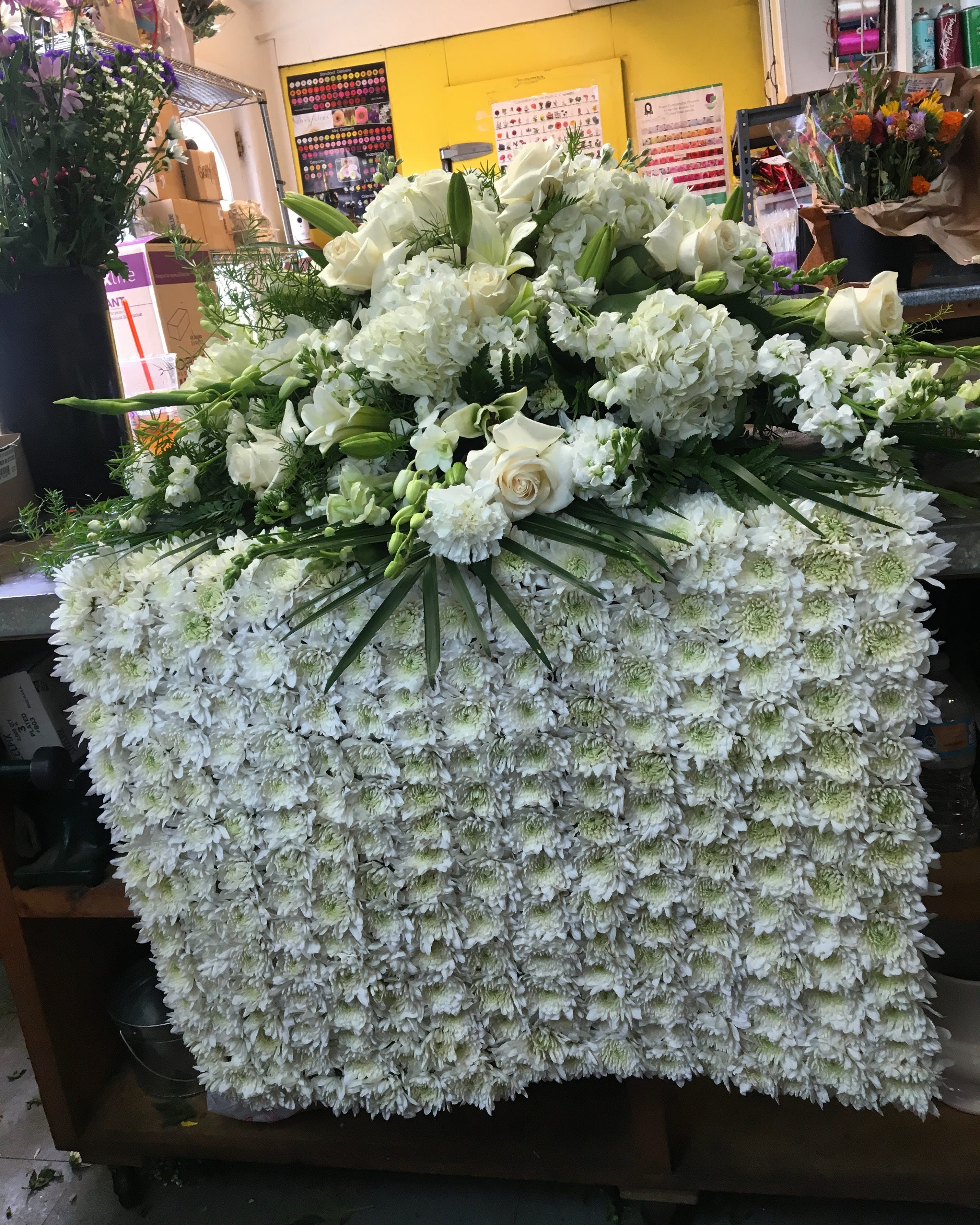 Elegant White Casket Spray with Blanket - A beautiful elegant casket spray with a blanket draped over the casket