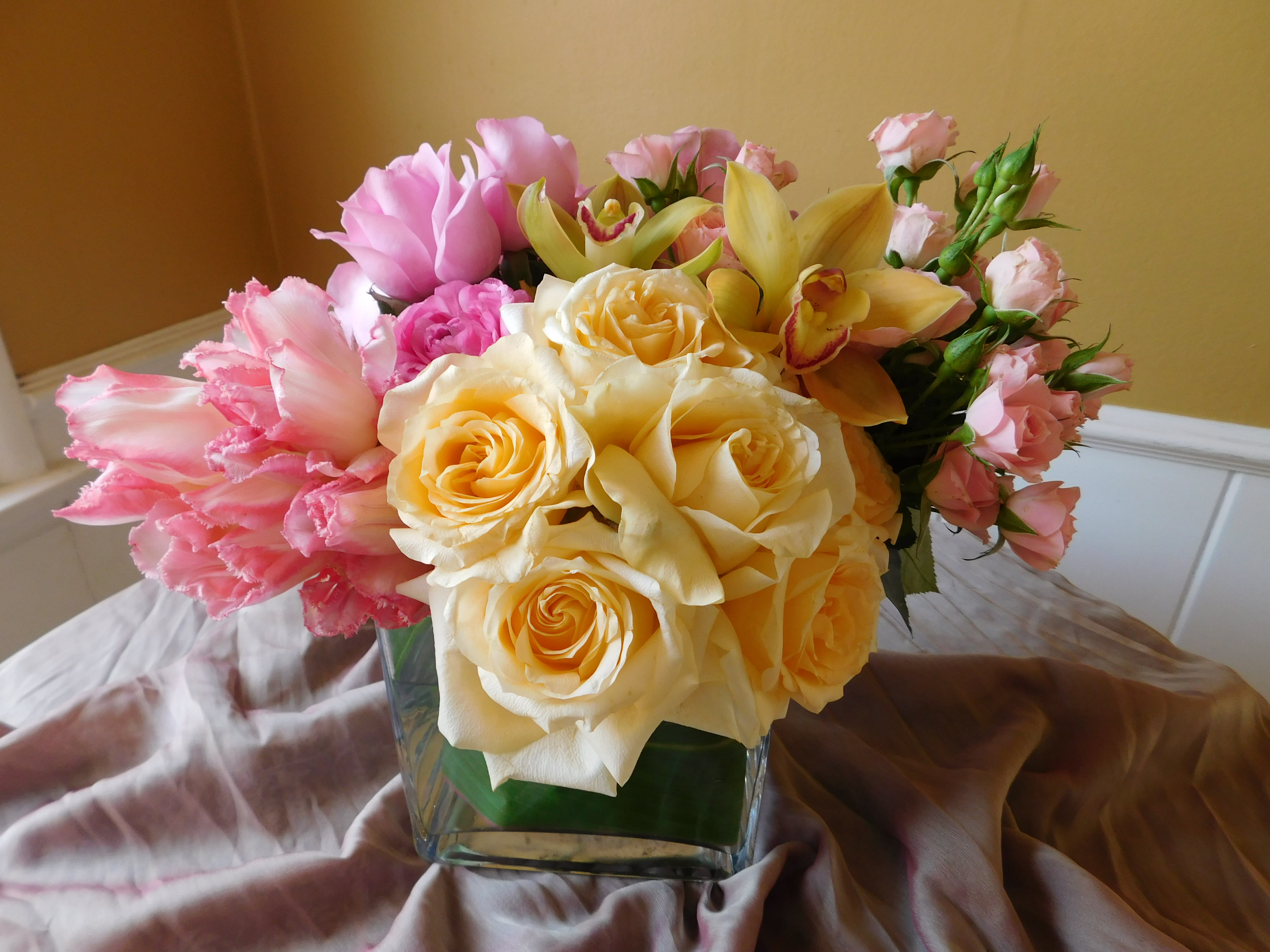 Sweet Sensation - Bright yellow Roses, soft pink Tulips and Cymbidium Orchids bunched up to design an elegant yet simple and sweet floral arrangement.  Comparable substitutes will be used for seasonal flowers.