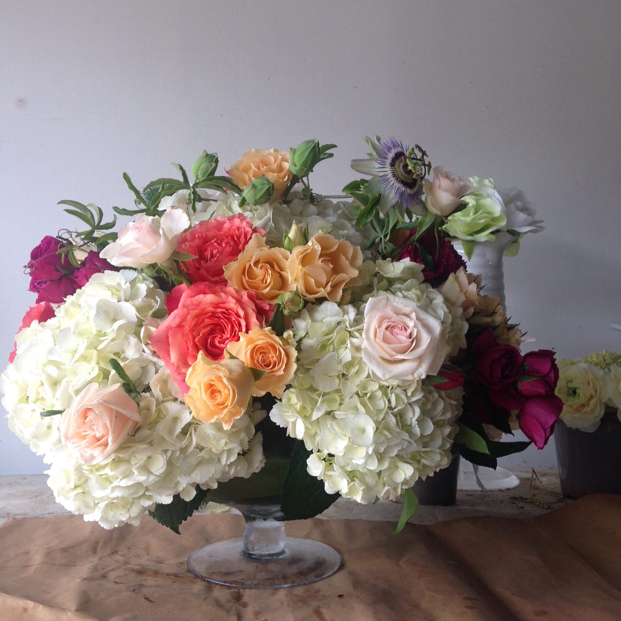 A little garden - Fluffy white hydrangeas with bright garden roses, passion flower and lilies worked with beautiful colorful peonies to create a stunning arrangement.