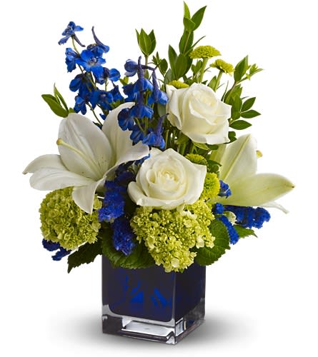 Serenade in Blue - A song for the eyes, this exquisitely lyrical bouquet in a chic contemporary glass cube vase is sure to impress anyone. Those with an eye for design are in for a special treat.  The stunning bouquet includes white Asiatic lilies, viburnum, dark blue delphinium, white roses, green button spray chrysanthemums and blue statice accented with assorted greens.  Delivered in a blue contemporary glass cube vase.  Bouquet is approximately 16â H x 13â W  Orientation: All-Around  As Shown : TFWEB606