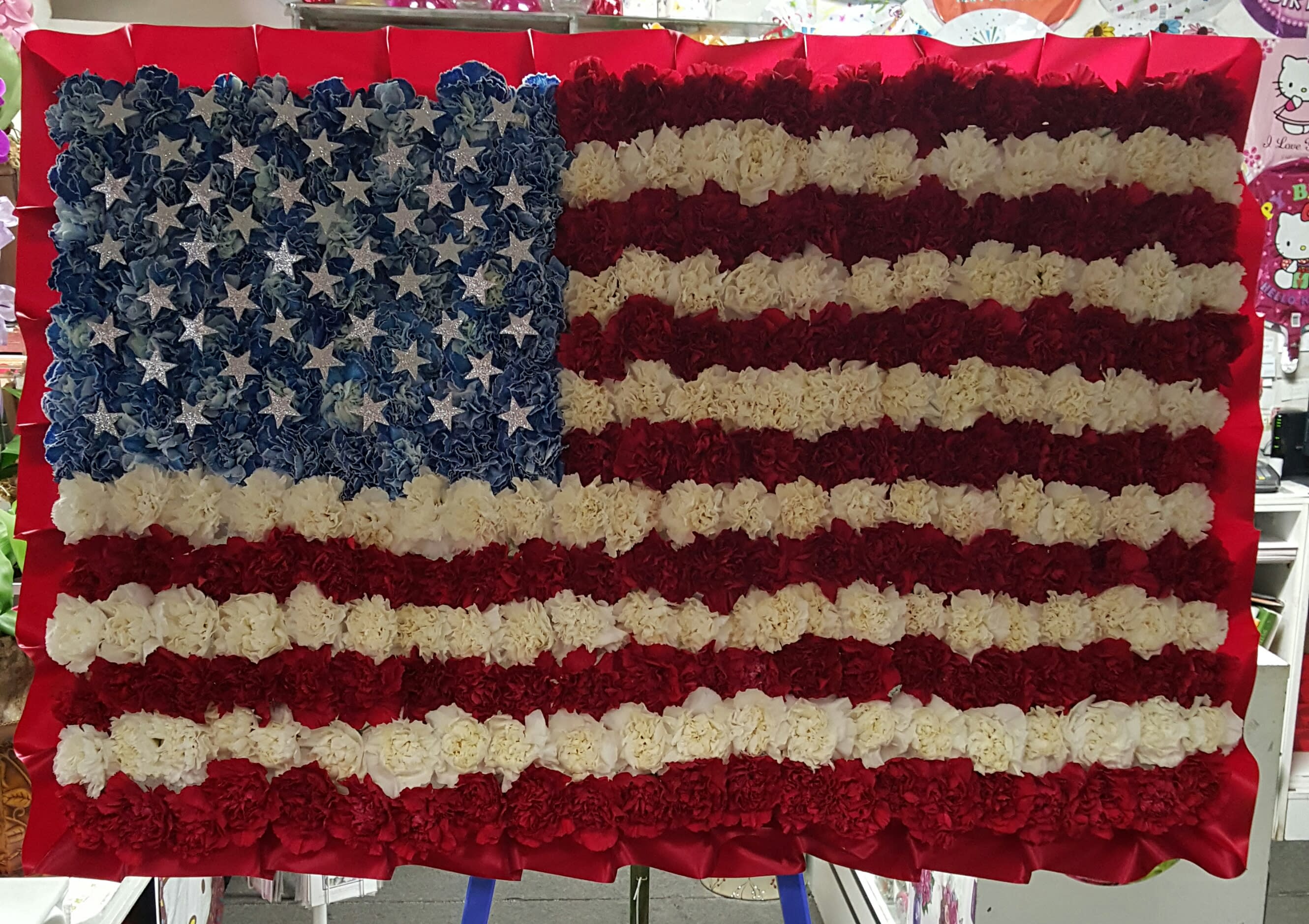 American flag American flag - 24" x 36" American flag arranged in red, white and blue carnation. 50 cut out silver star are placed over the blue carnation.