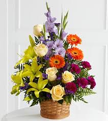 Forever Dear Arrangement ( Deluxe Shown ) Forever Dear Arrangement ( Deluxe Shown ) - Forever Dear™ Arrangement is a colorful assortment of our finest blooms. Crème de la Crème roses, yellow Asiatic lilies, orange gerbera daisies, lavender gladiolus, plum carnations and purple statice are accented with leatherleaf and sword fern stems. Gorgeously displayed in a natural buff woodchip basket, this arrangement will add to the natural beauty and serenity of thier final tribute.