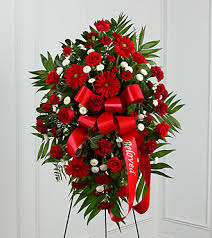 Treasured Memories - Treasured Memories™ Standing Spray is a rich and colorful way to express your unending love and devotion to the departed. An exceptional arrangement of red roses, burgundy carnations, burgundy mini carnations, red gerbera daisies and white button poms are accented with a variety of lush greens. A red ribbon with the word, &quot;Beloved&quot;, embossed in a gold metallic lettering, finishes this beautiful display for their final farewell service. 