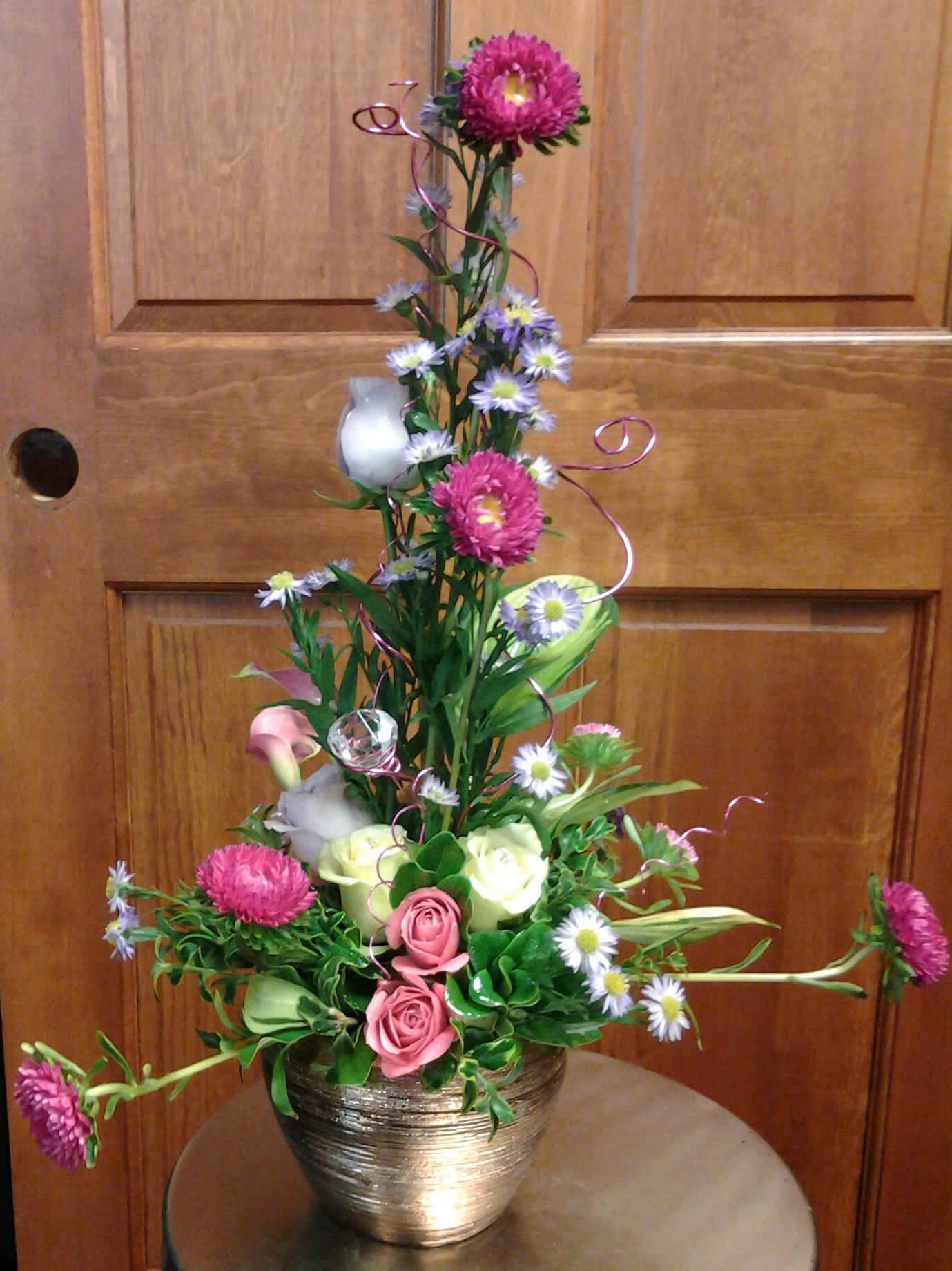 Pink &amp; purple birthday fun - With a mixture of roses, asters, other flowers along with some bling this will be fun for any young lady's birthday or just because. Containers may vary.